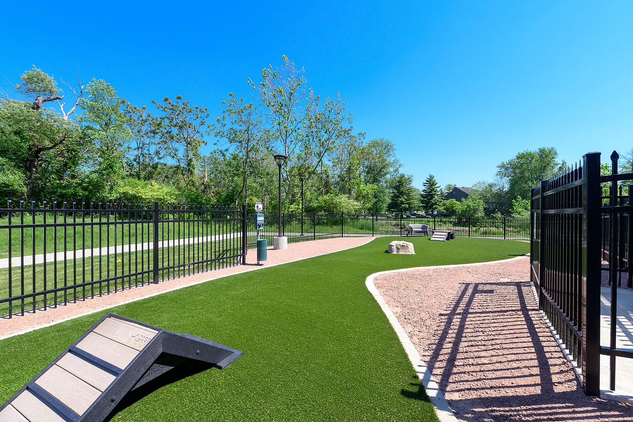 Inviting dog park with lush green spaces, agility equipment, and secure fencing, perfect for pet-friendly living.
