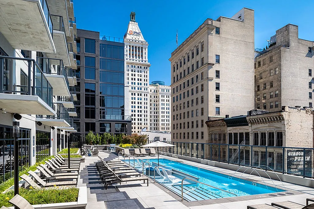 Elegant urban apartment terrace with a chic swimming pool and lounge chairs, surrounded by modern architecture and cityscape views.