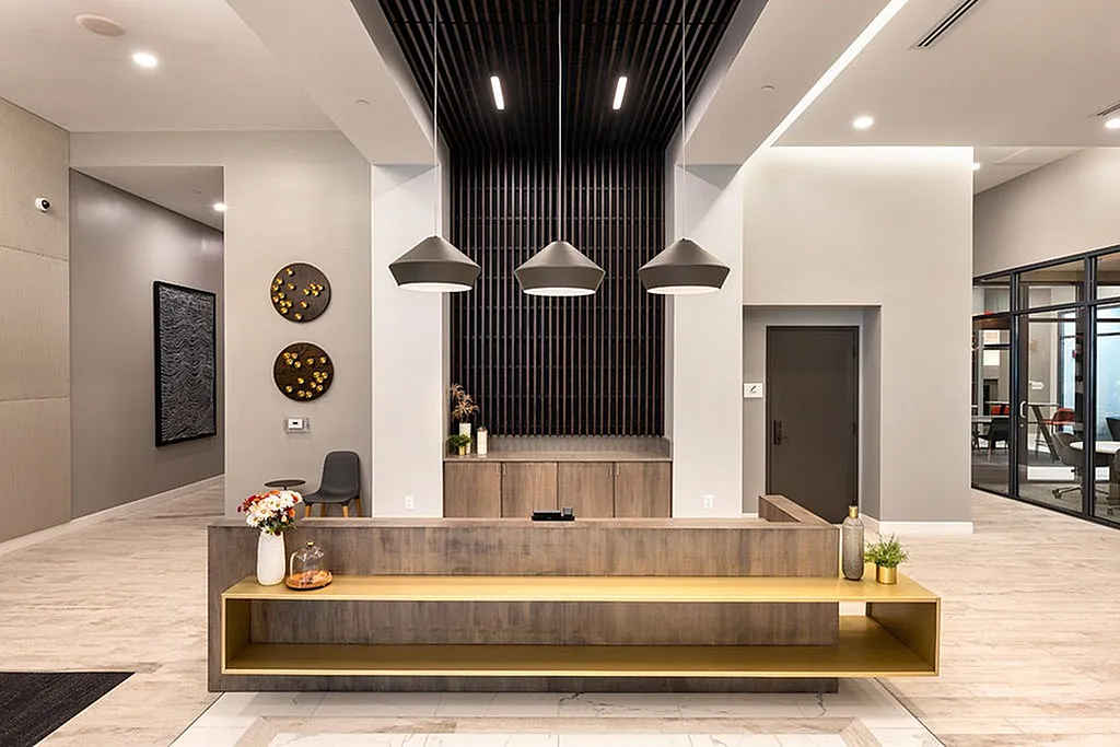 Elegant apartment lobby featuring modern design with stylish wooden accents, ambient lighting, and welcoming decor.