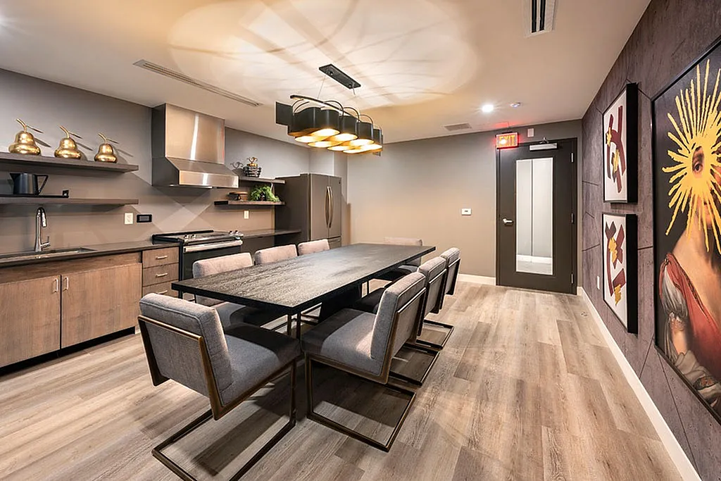 Modern kitchen with sleek cabinetry, stainless steel appliances, and elegant dining area, complemented by contemporary art.