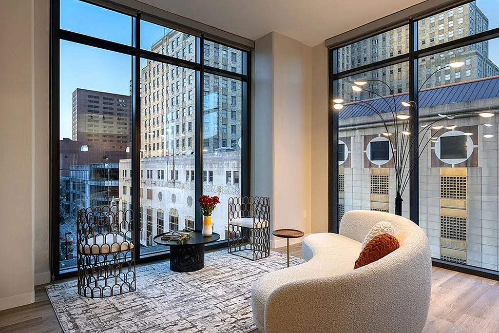 Chic urban apartment with floor-to-ceiling windows, offering breathtaking city views, modern furniture, and cozy seating.