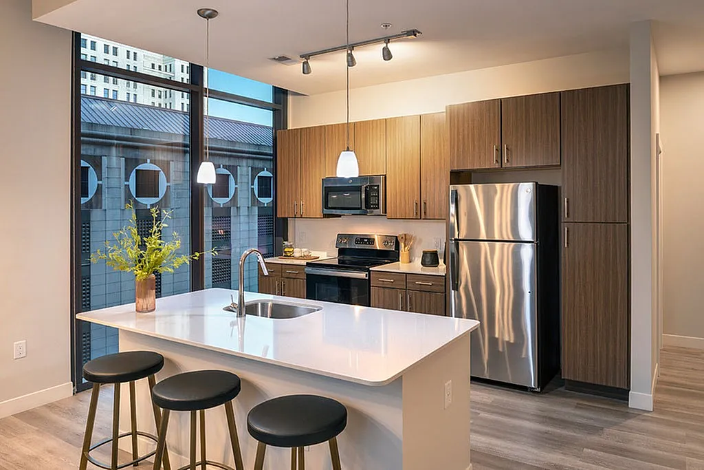 Chic modern kitchen with stainless steel appliances, elegant pendant lighting, and expansive windows offering city views.
