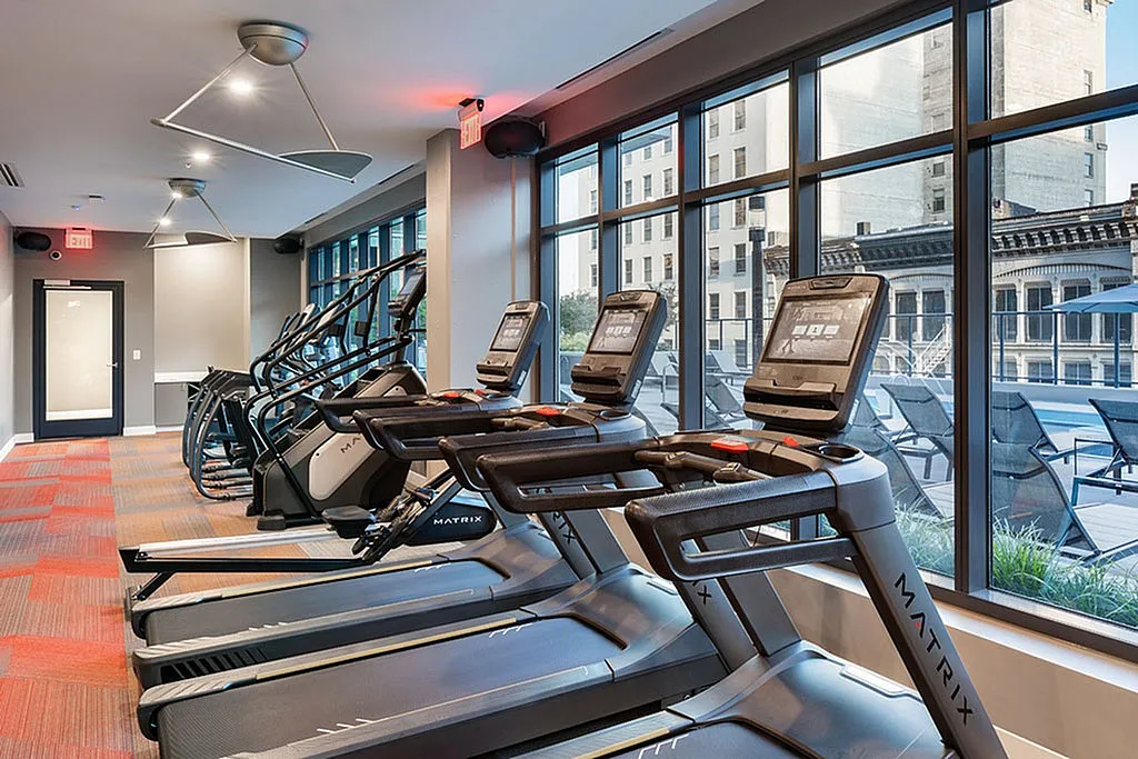 Modern fitness center with state-of-the-art treadmills and large windows offering a city view.