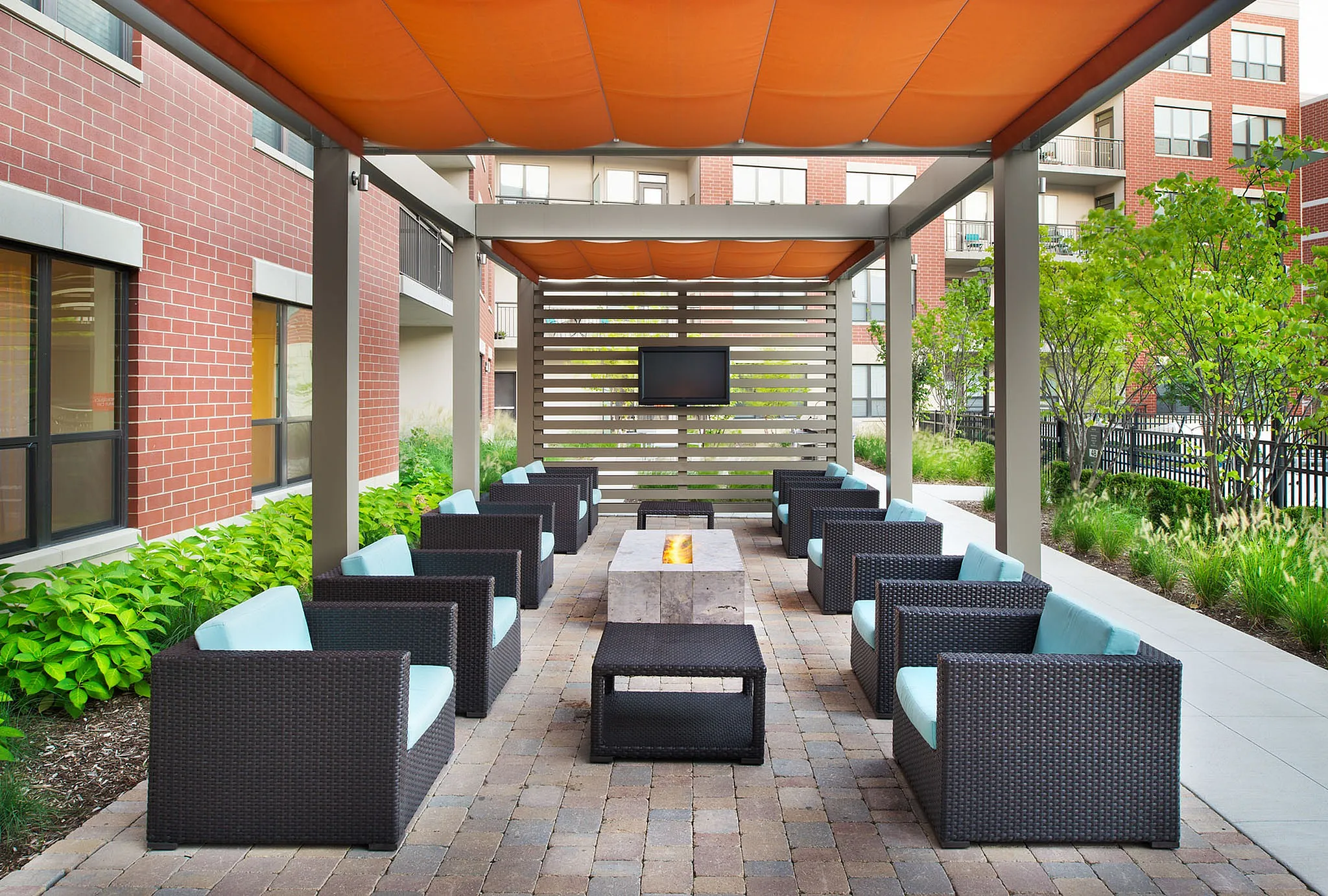 Chic outdoor lounge with modern wicker chairs, shaded pergola, and cozy fire pit, perfect for entertaining.