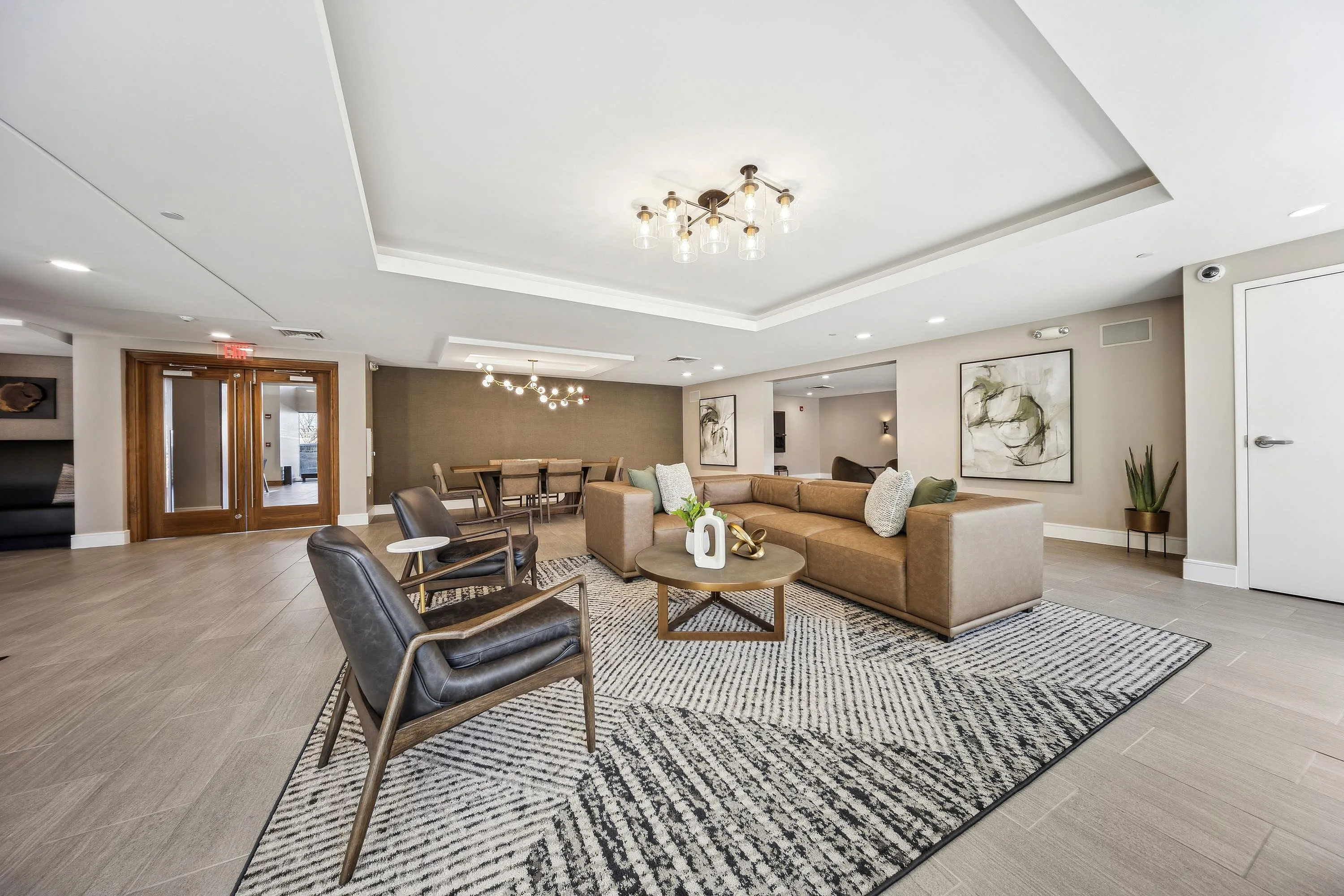 Elegant communal living area with contemporary decor, featuring a plush sectional sofa, modern leather chairs, and stylish lighting perfect for relaxation and socializing.