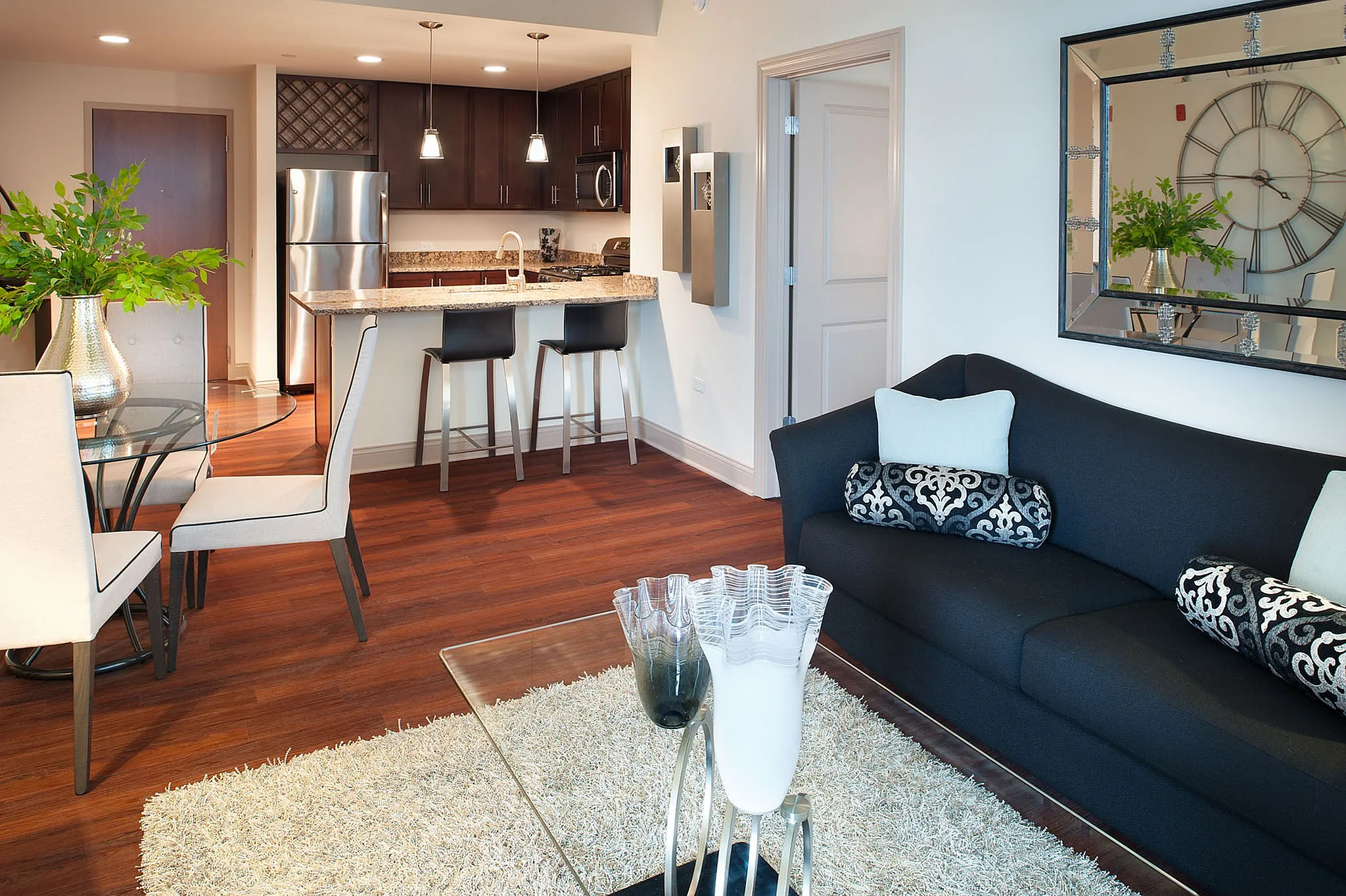 Chic apartment living area featuring elegant dark wood kitchen, cozy seating, and stylish dining space with vibrant decor.