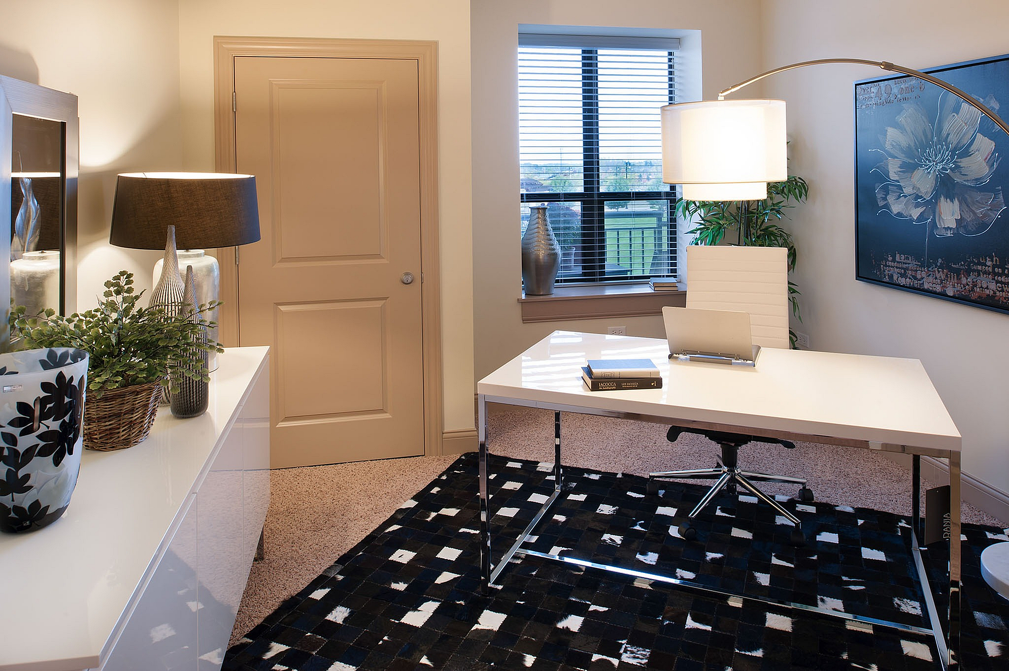 Elegant home office with modern white desk and stylish decor, featuring lush indoor plants and large window views.