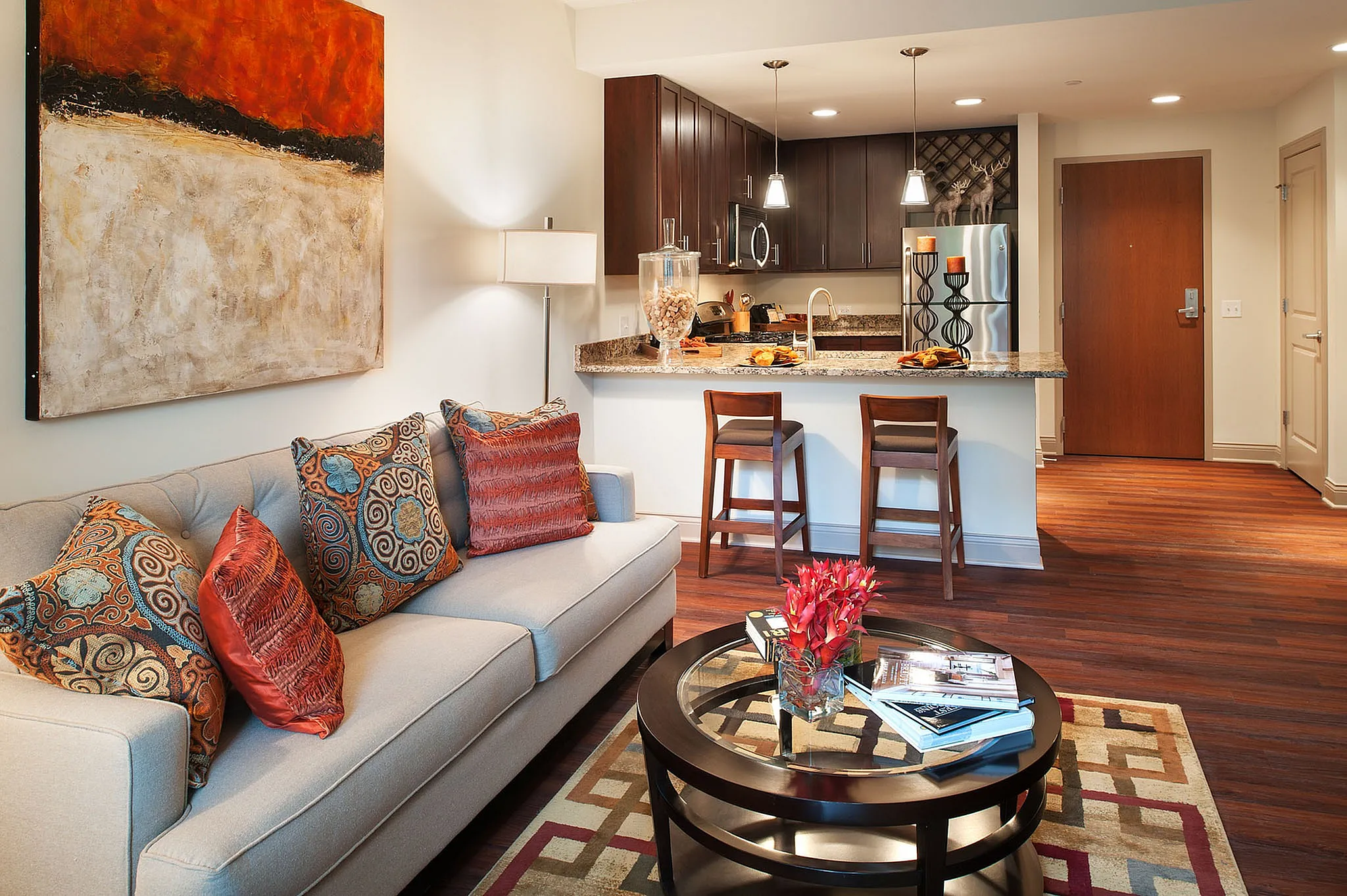 Modern apartment interior featuring a cozy living room with elegant decor, open kitchen with dark wood cabinetry, and stylish breakfast bar seating.