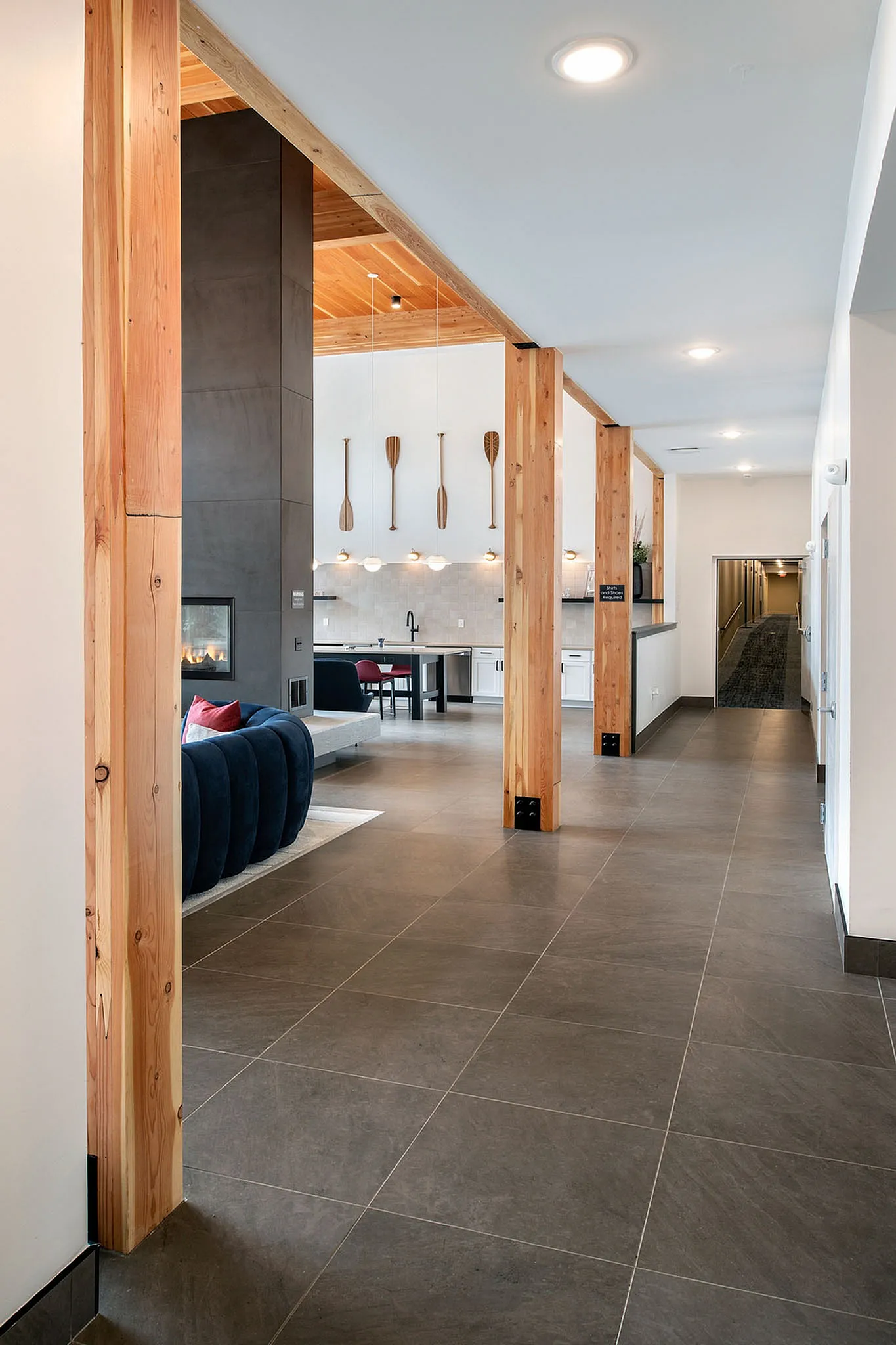 Contemporary open-plan living area featuring sleek wooden columns, modern furniture, and a chic kitchen. Perfect for stylish urban living.