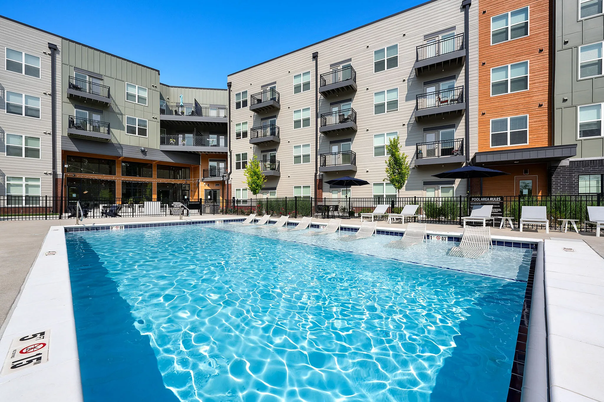 Modern apartment complex with balconies and a sparkling outdoor pool, perfect for relaxing in style.