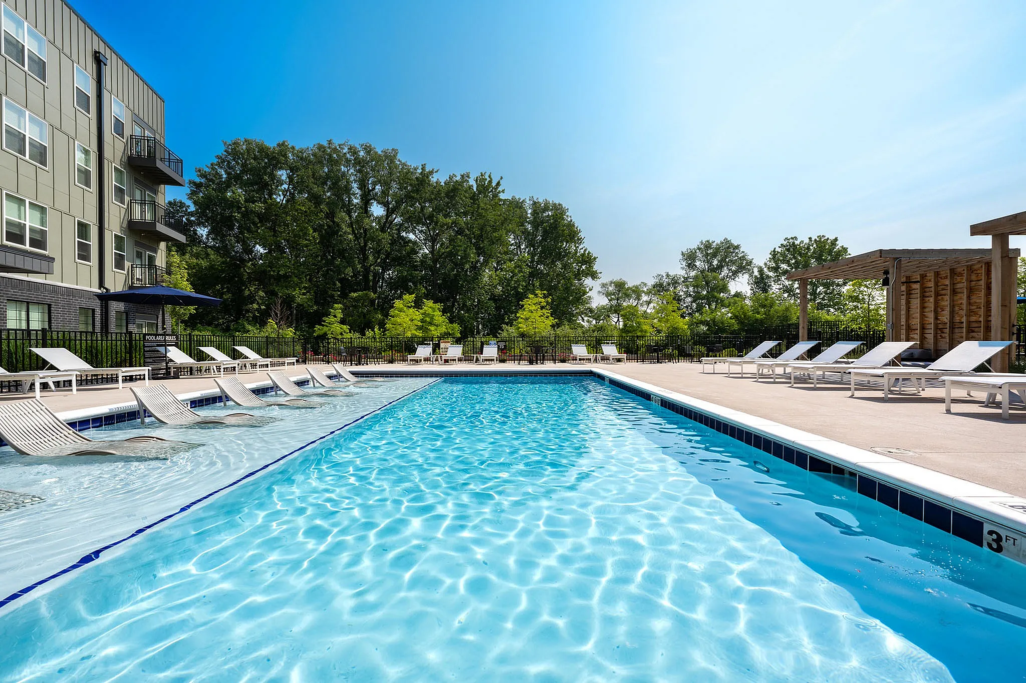 Luxurious apartment poolside retreat featuring crystal-clear water, stylish lounge chairs, and lush greenery for a serene outdoor escape.