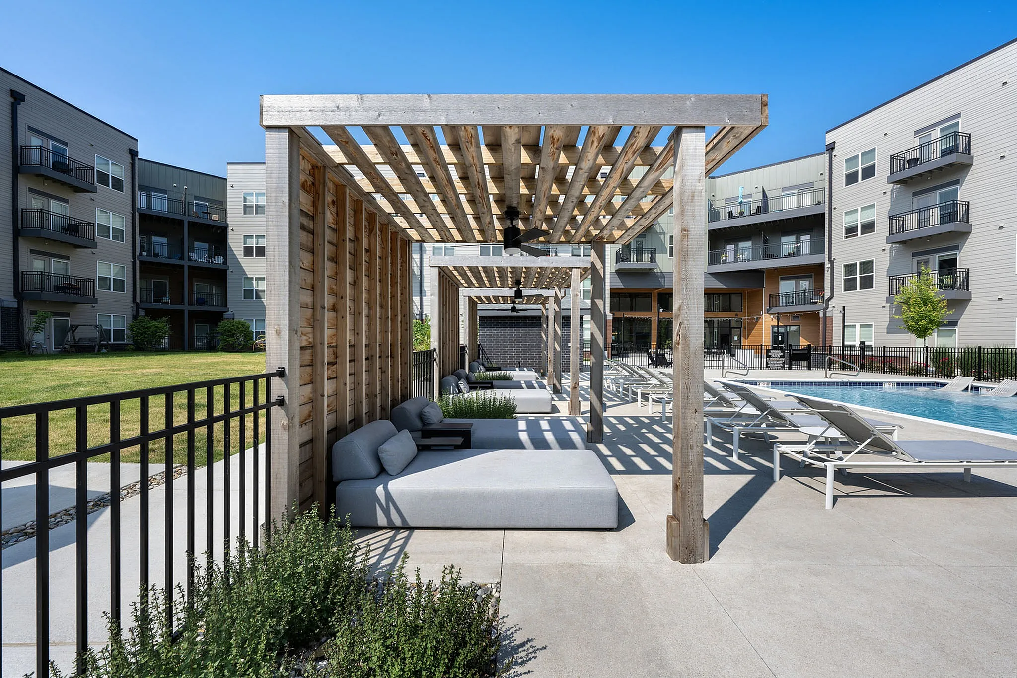 Modern apartment complex with luxurious poolside cabanas and sun loungers, offering a relaxing outdoor retreat.