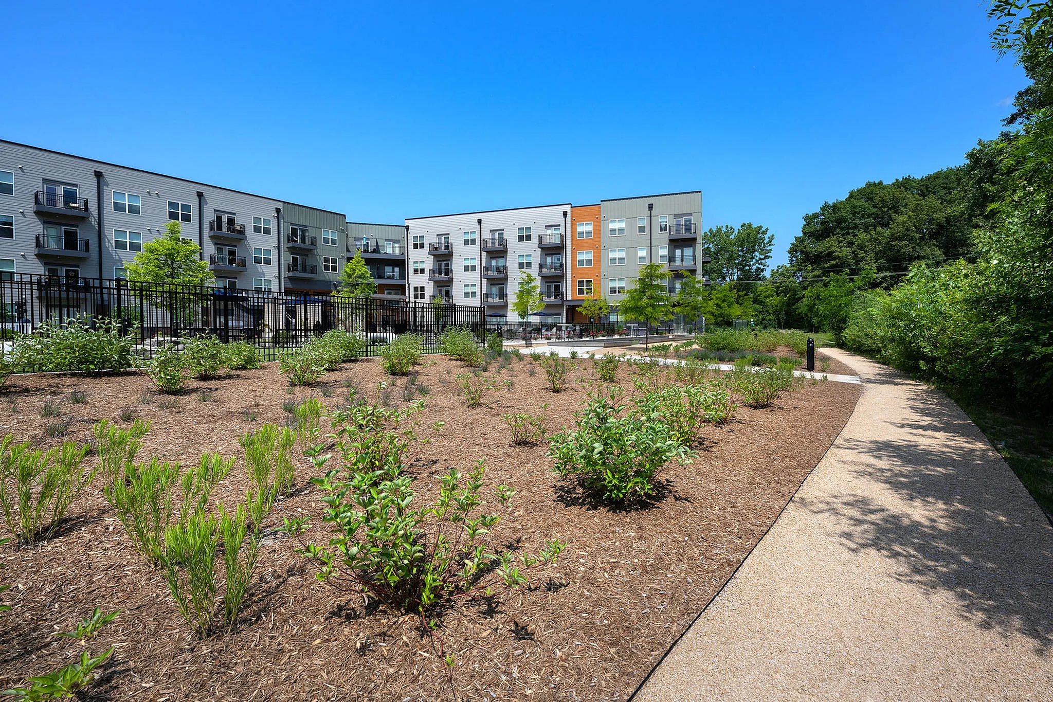 Modern apartment complex with beautifully landscaped gardens and a clear blue sky.