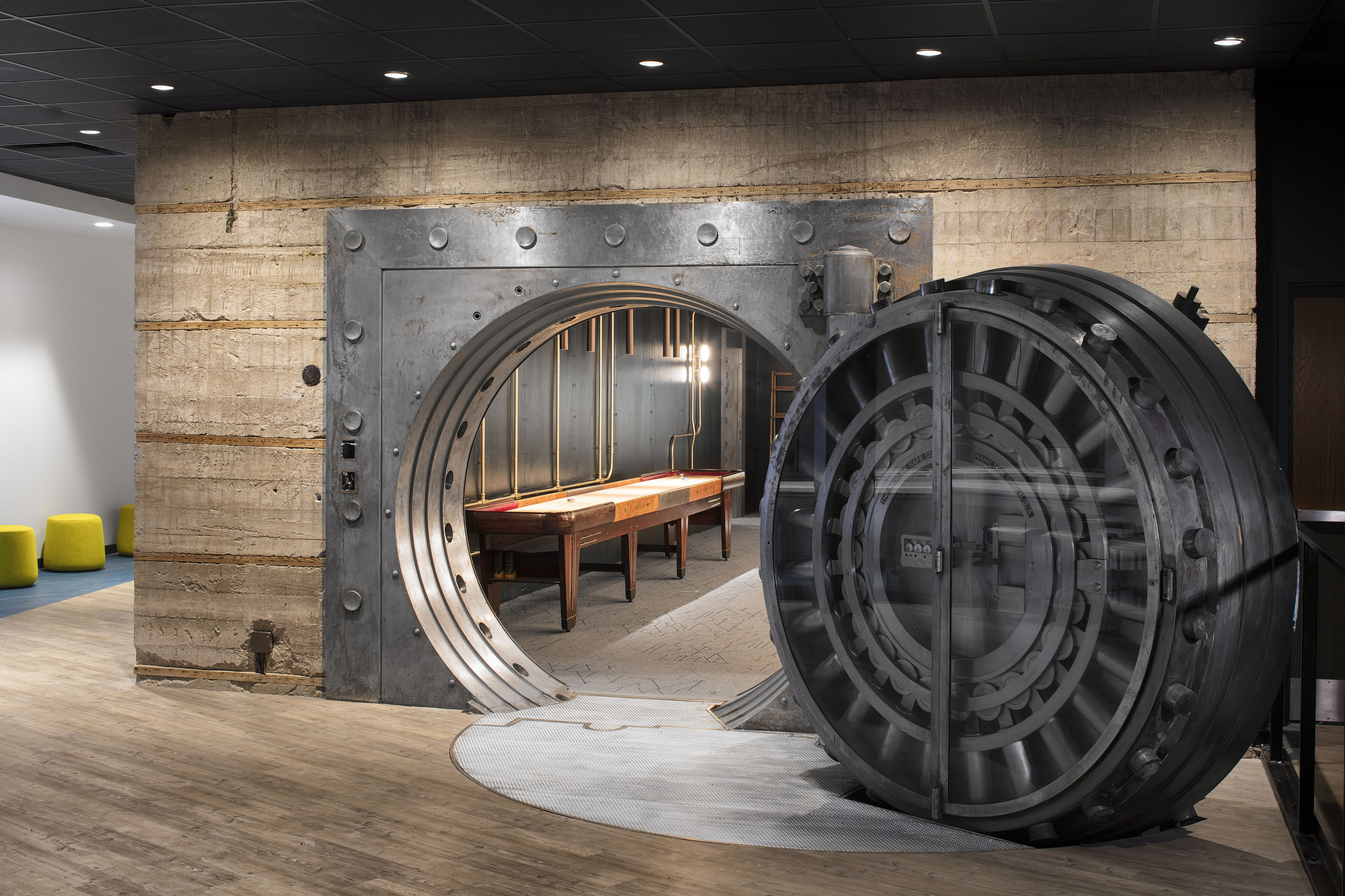 Unique apartment feature with a repurposed vault door leading to an elegant entertainment area with ambient lighting.