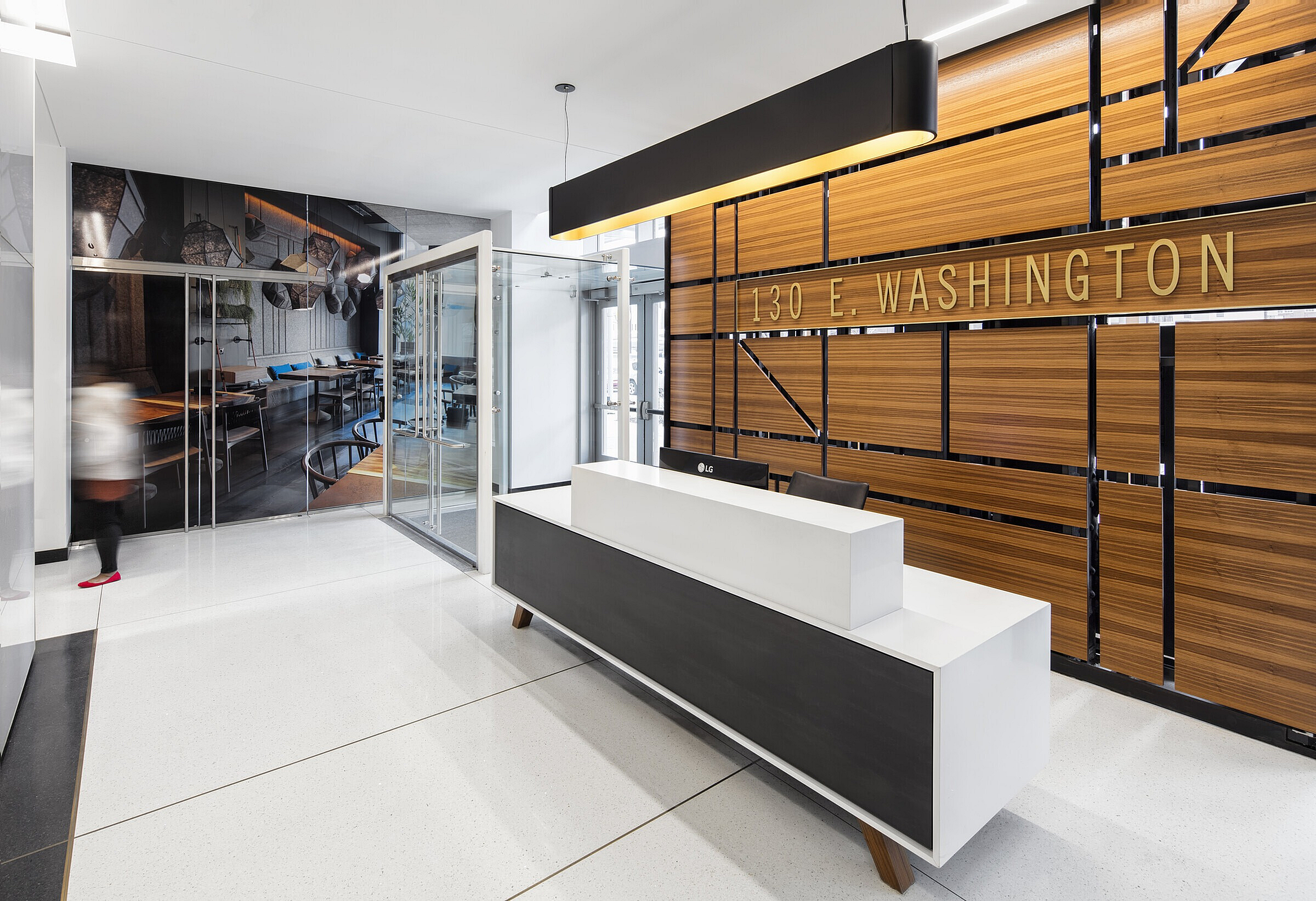 Modern lobby featuring sleek design with a minimalist reception desk, stylish wood paneling, and elegant lighting at 130 E. Washington.
