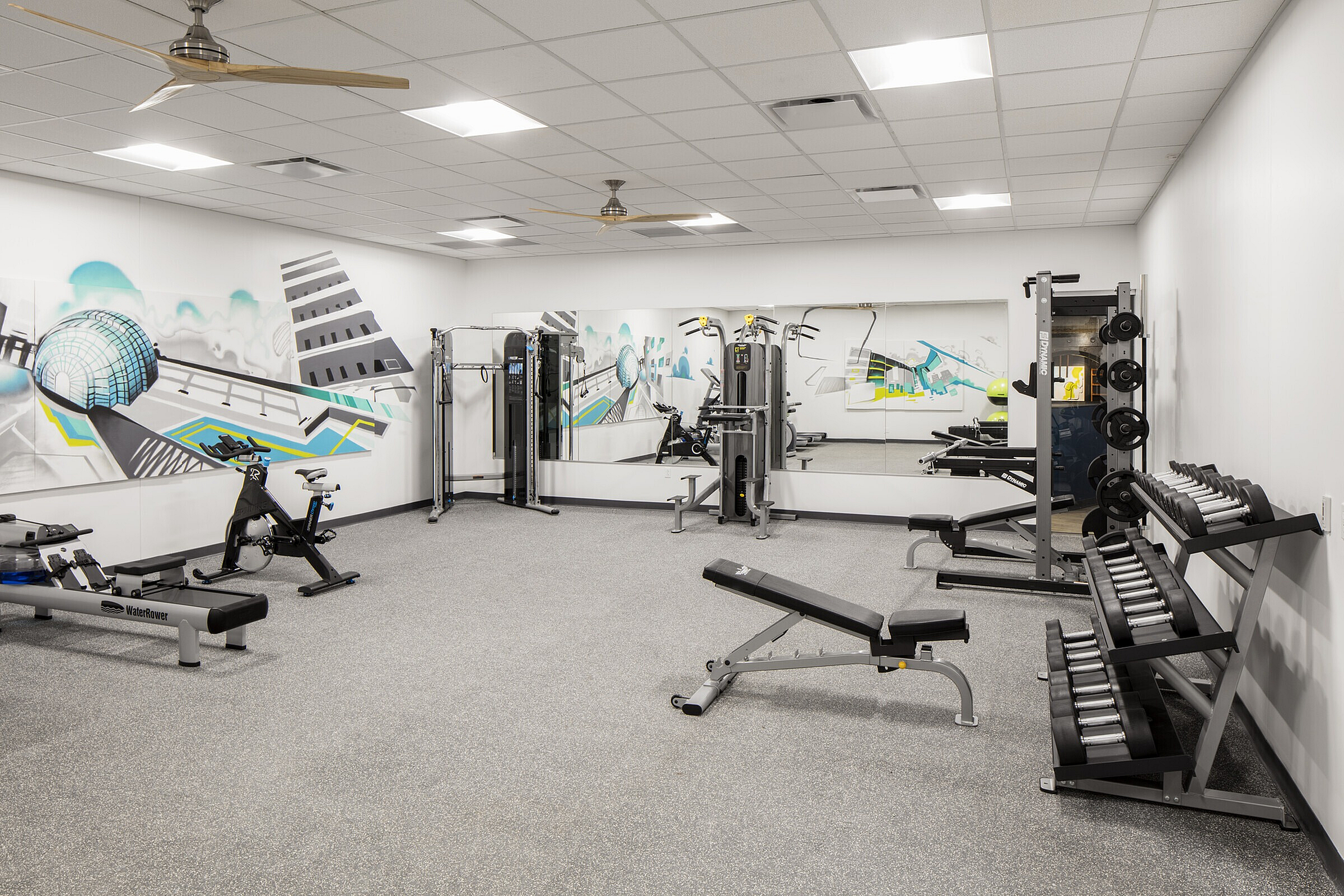 Modern fitness center with sleek equipment, vibrant mural art, and well-lit workout space designed for comfort and motivation.