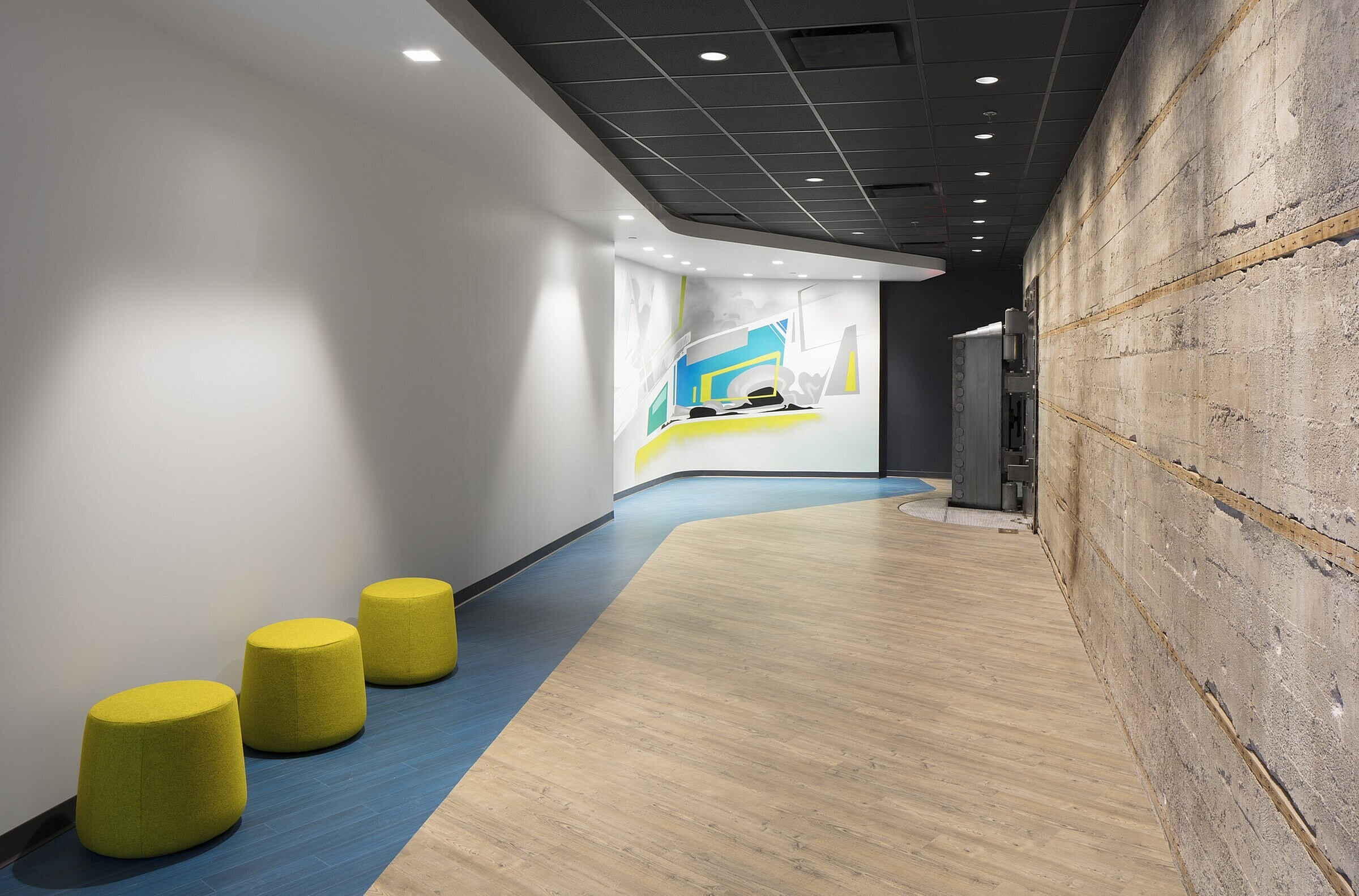 Modern hallway with vibrant wall art and stylish seating, featuring a blend of rustic brick and sleek design.