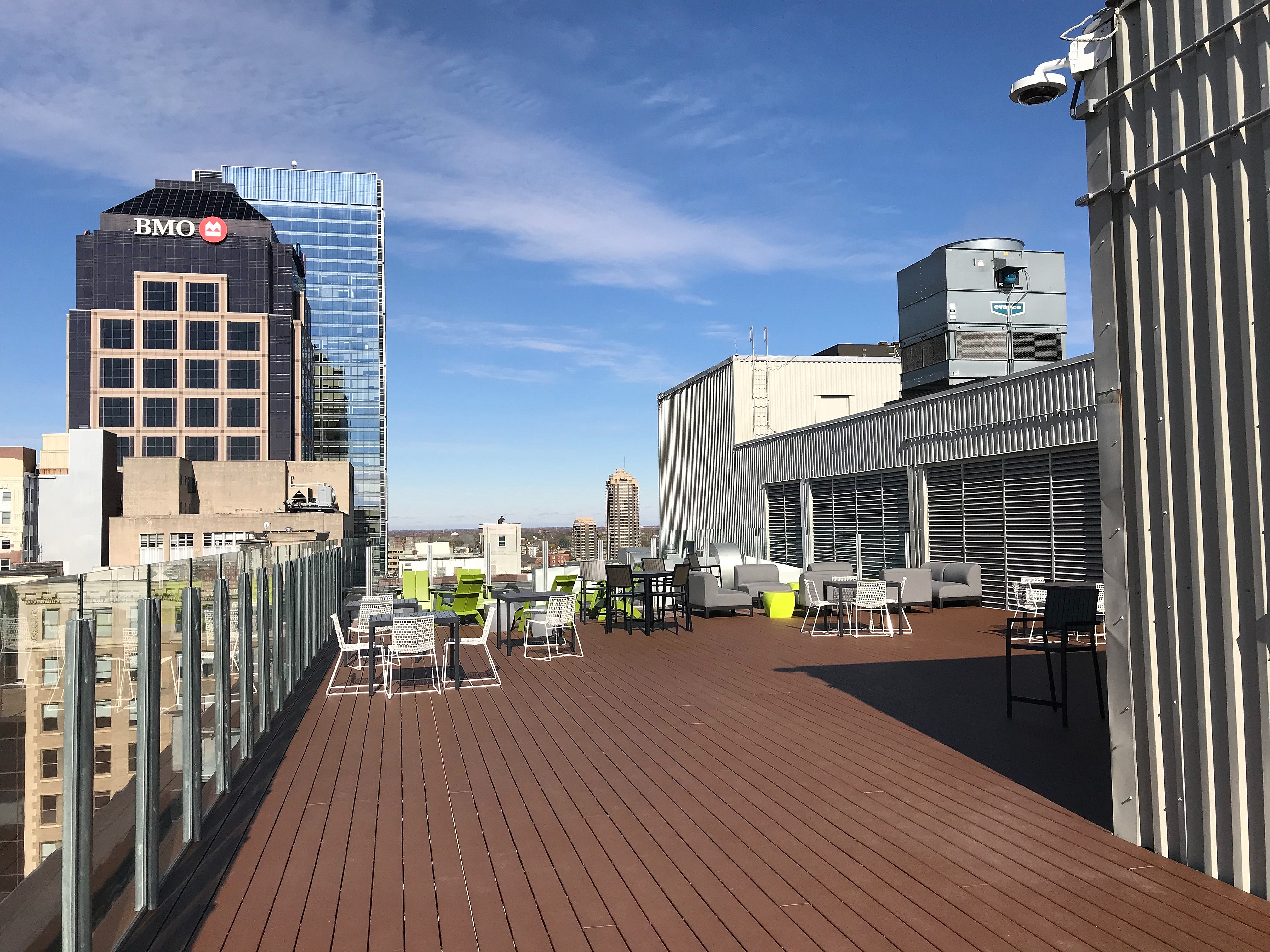 Inviting rooftop terrace with modern seating, stunning cityscape views, and ample space for relaxation under a bright blue sky.