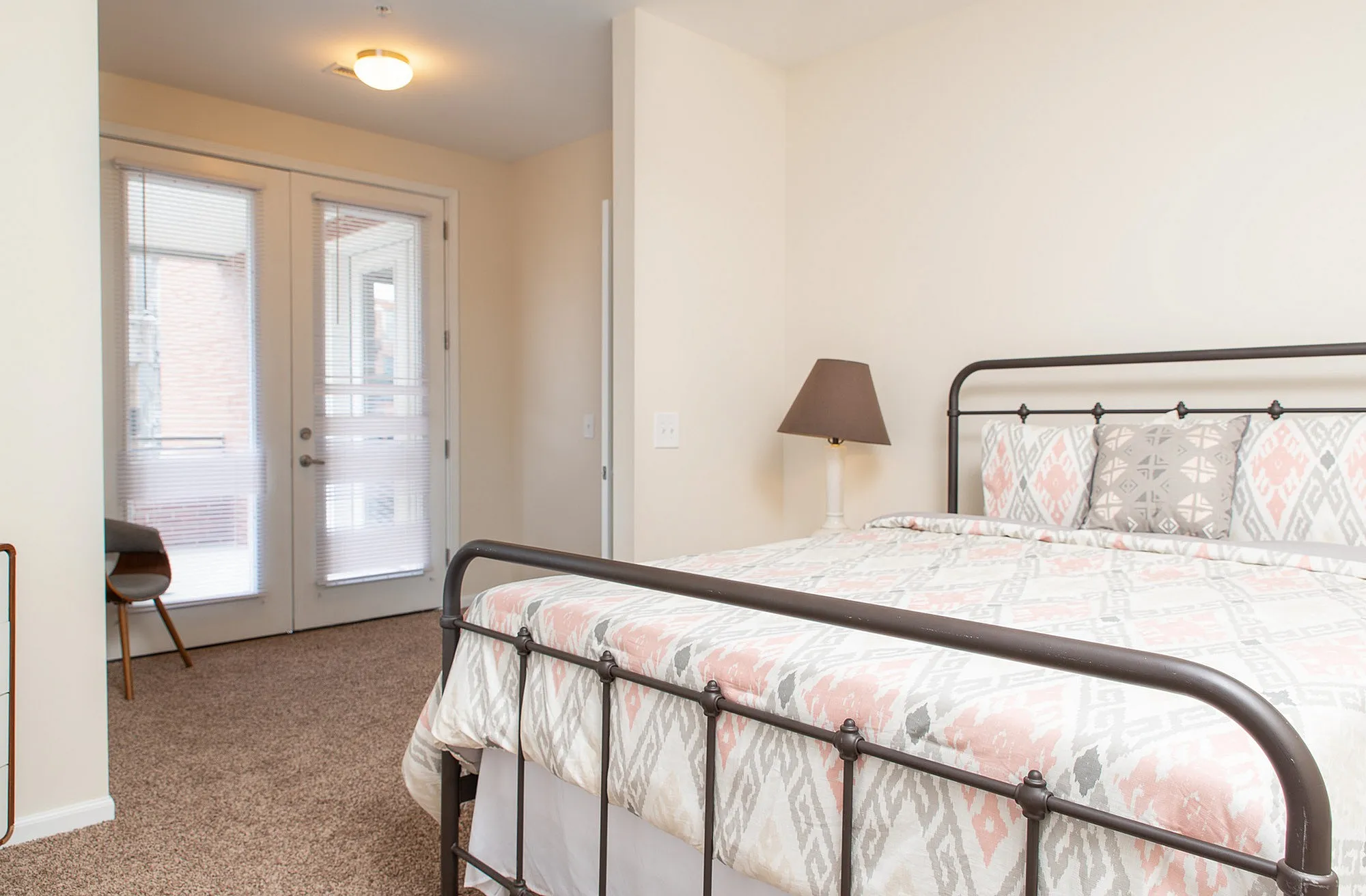Bright and inviting bedroom with a cozy bed, modern decor, and access to a private balcony through glass doors.