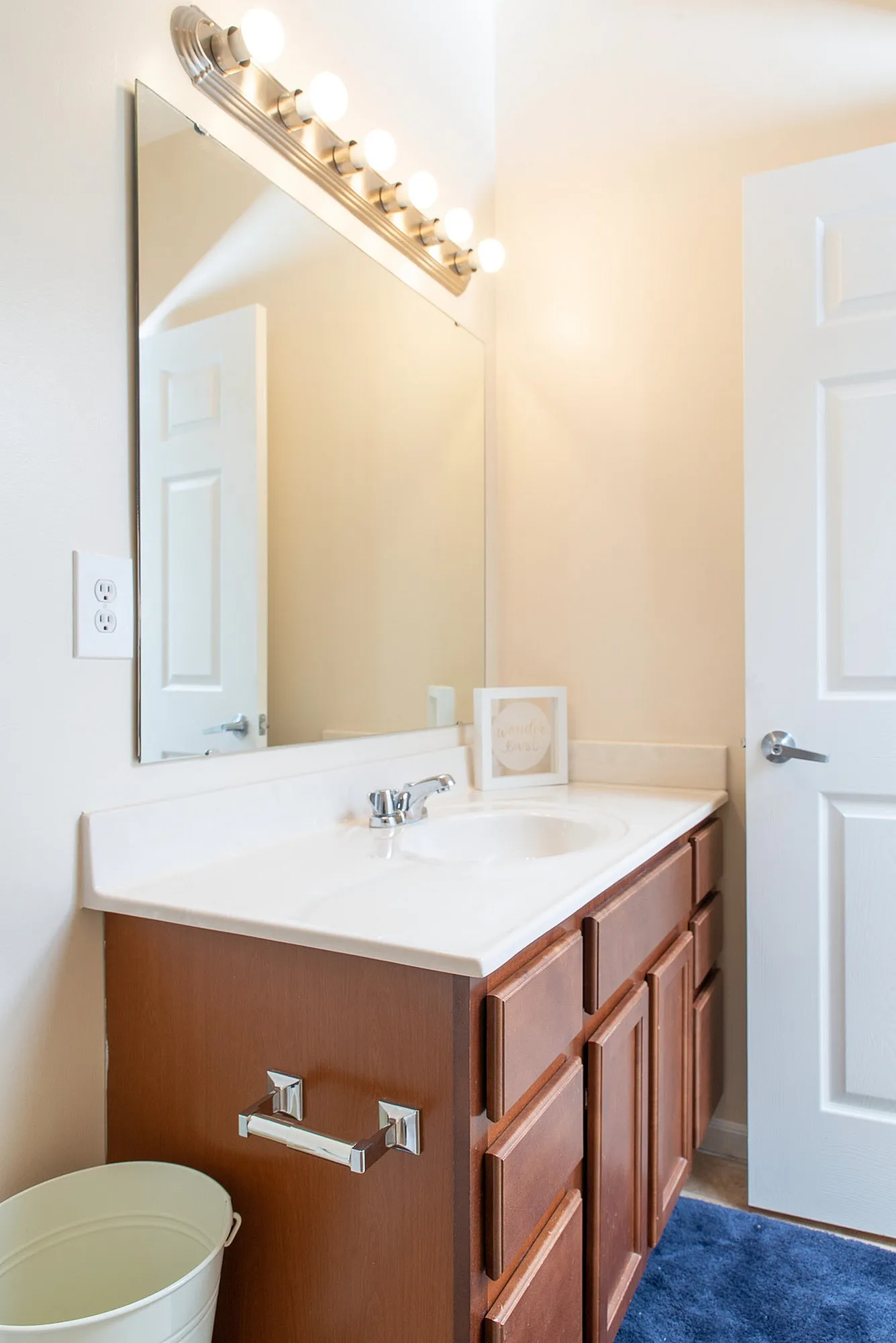 Elegant bathroom with a large mirror and modern lighting fixtures atop a stylish wooden vanity.