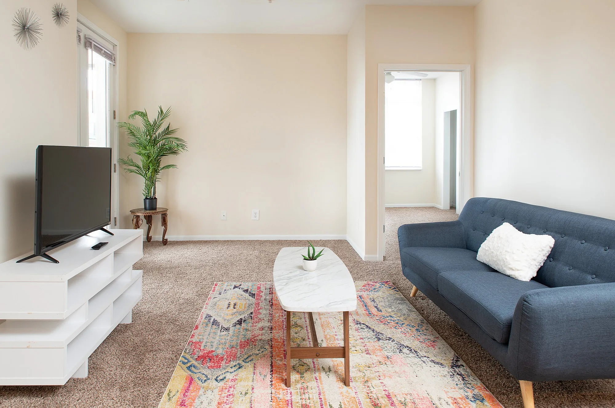 Bright and inviting living room with modern decor, featuring a plush blue sofa, a stylish marble coffee table, and a lush green plant adding a fresh touch.