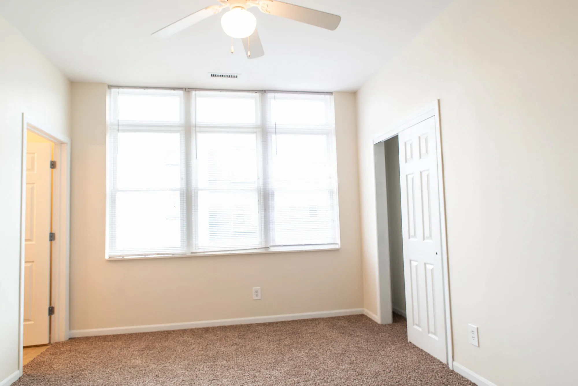 Bright, airy bedroom with plush carpet and large windows, perfect for a cozy retreat.