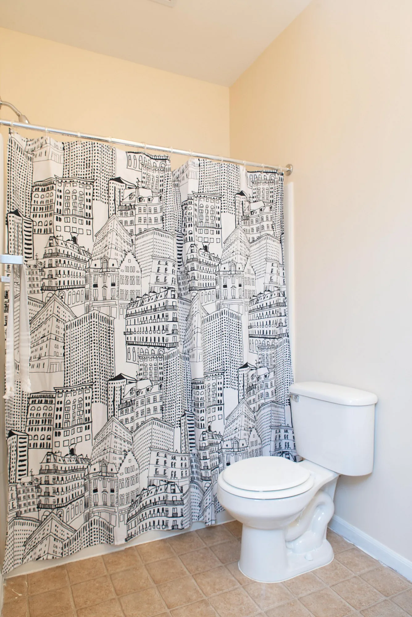 Bright bathroom with chic cityscape shower curtain and pristine tiles.