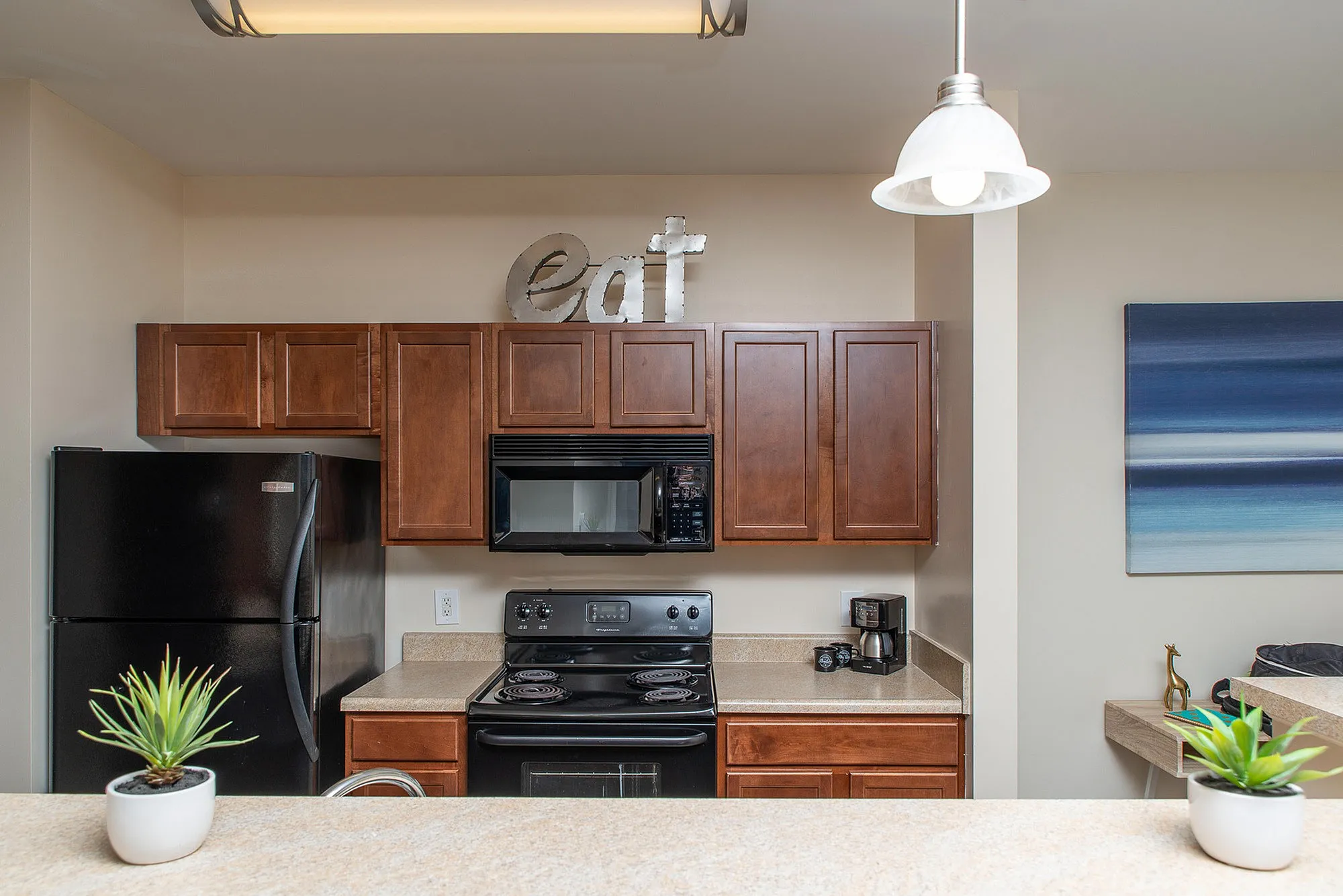 Elegant kitchen featuring rich wooden cabinets, sleek black appliances, and cozy lighting for a modern culinary experience.