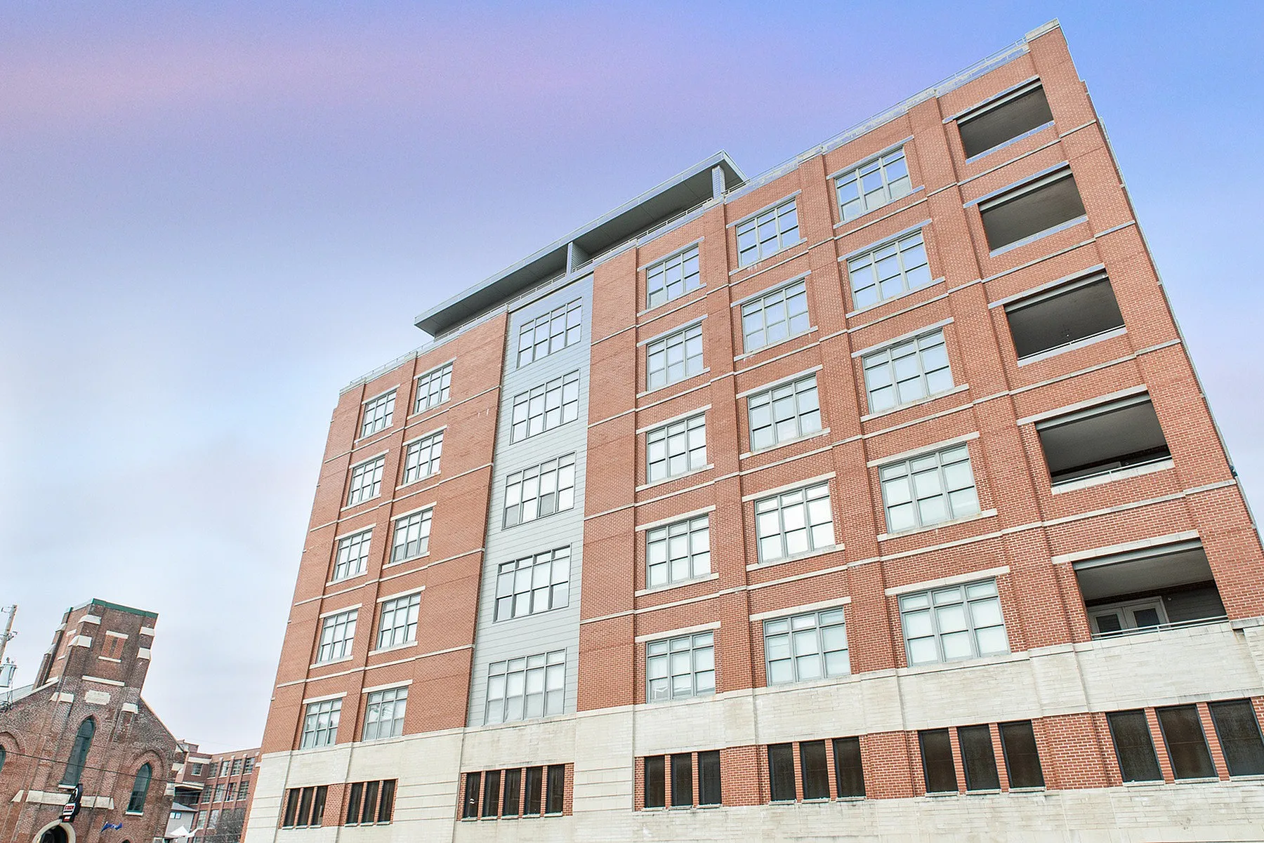 Modern brick apartment building with large windows, offering spacious urban living with a contemporary vibe.