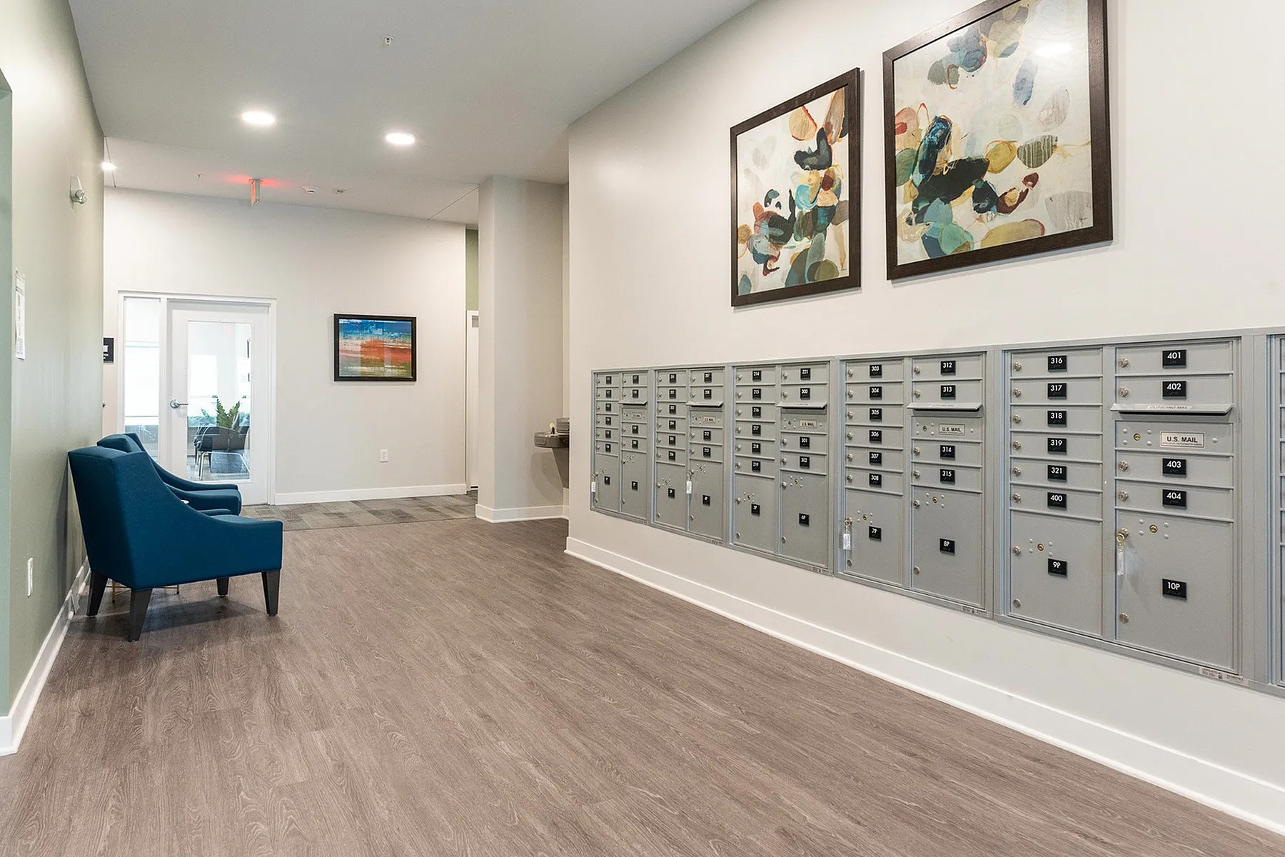Chic apartment lobby featuring modern mailboxes, elegant blue chairs, and contemporary artwork.