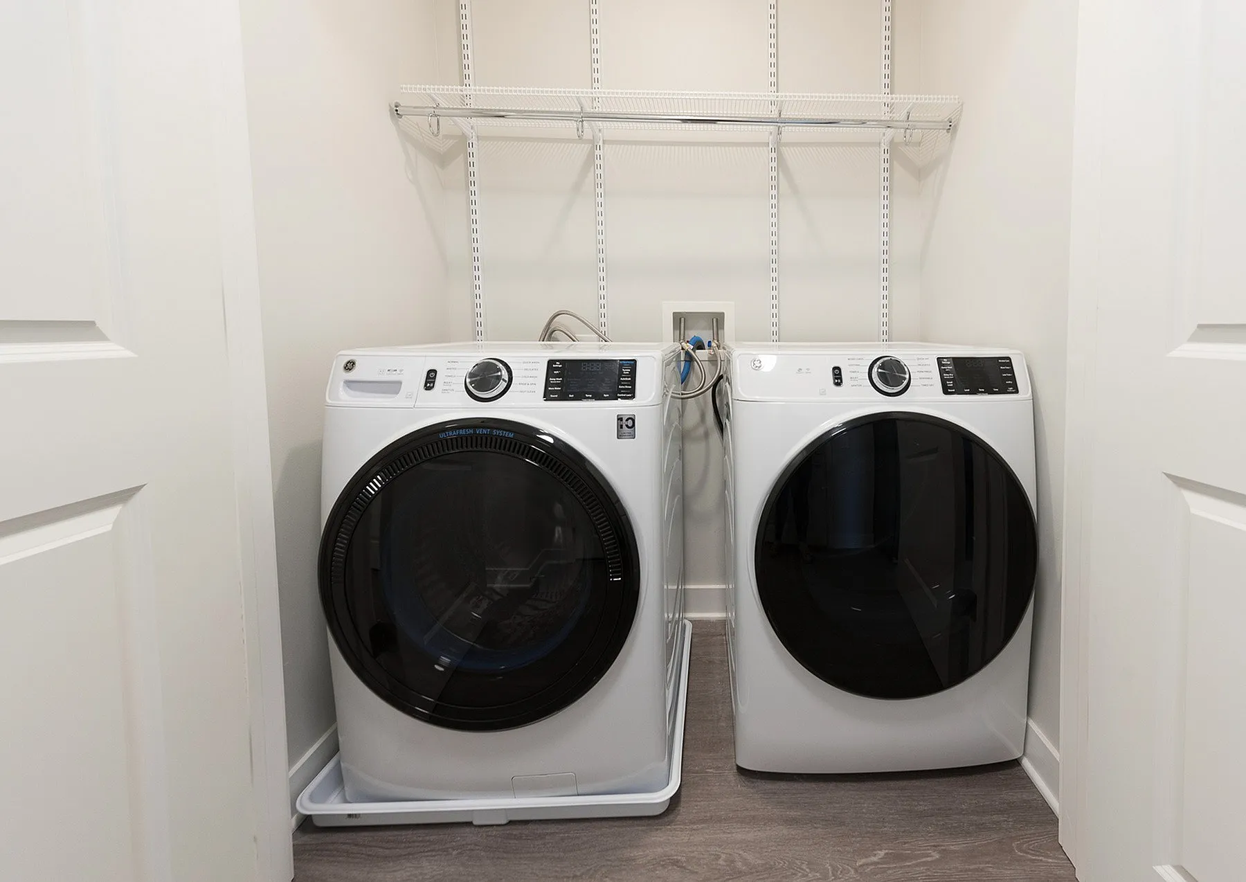 Modern laundry room featuring high-efficiency front-load washer and dryer with sleek shelving.
