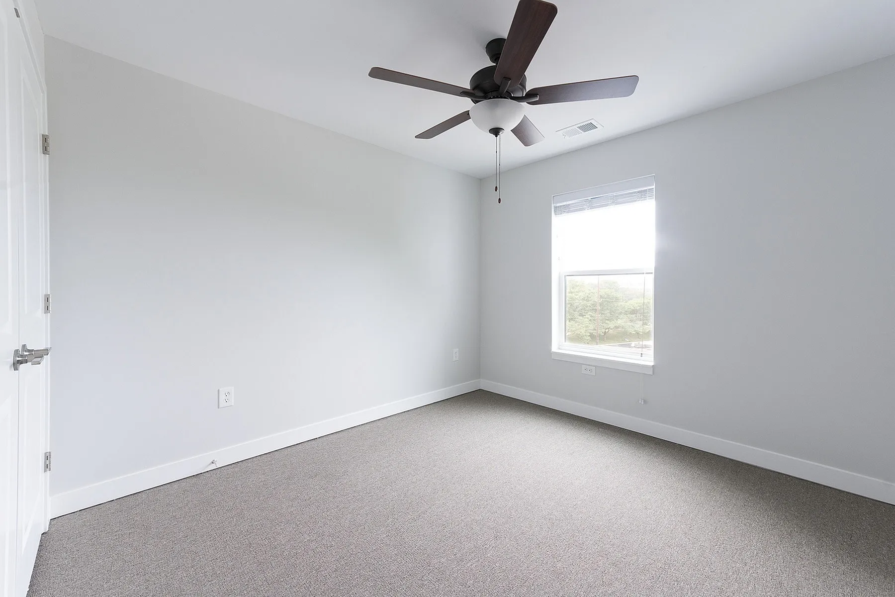 Bright and airy bedroom with modern ceiling fan and large window offering scenic views.