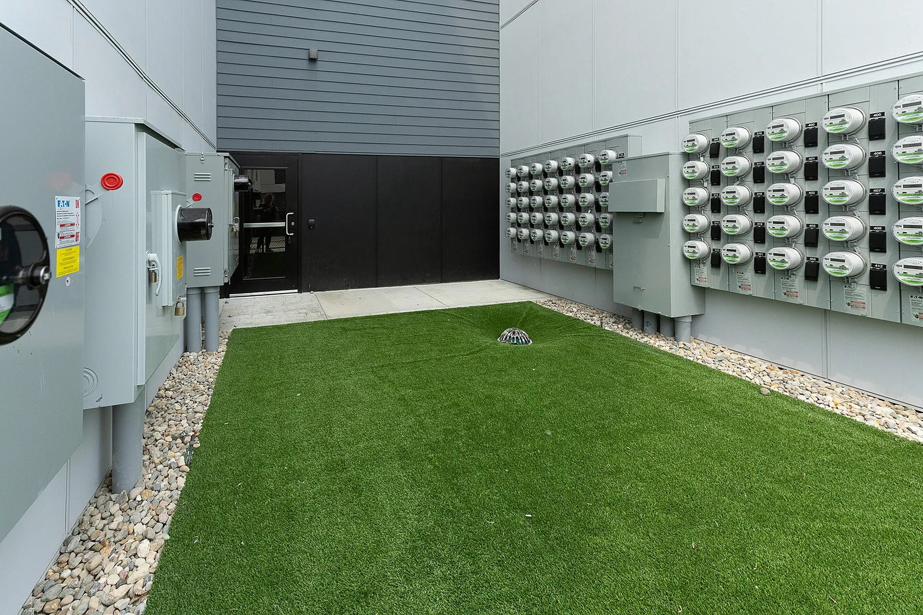 Modern utility area with neatly installed electrical meters and well-maintained green turf.
