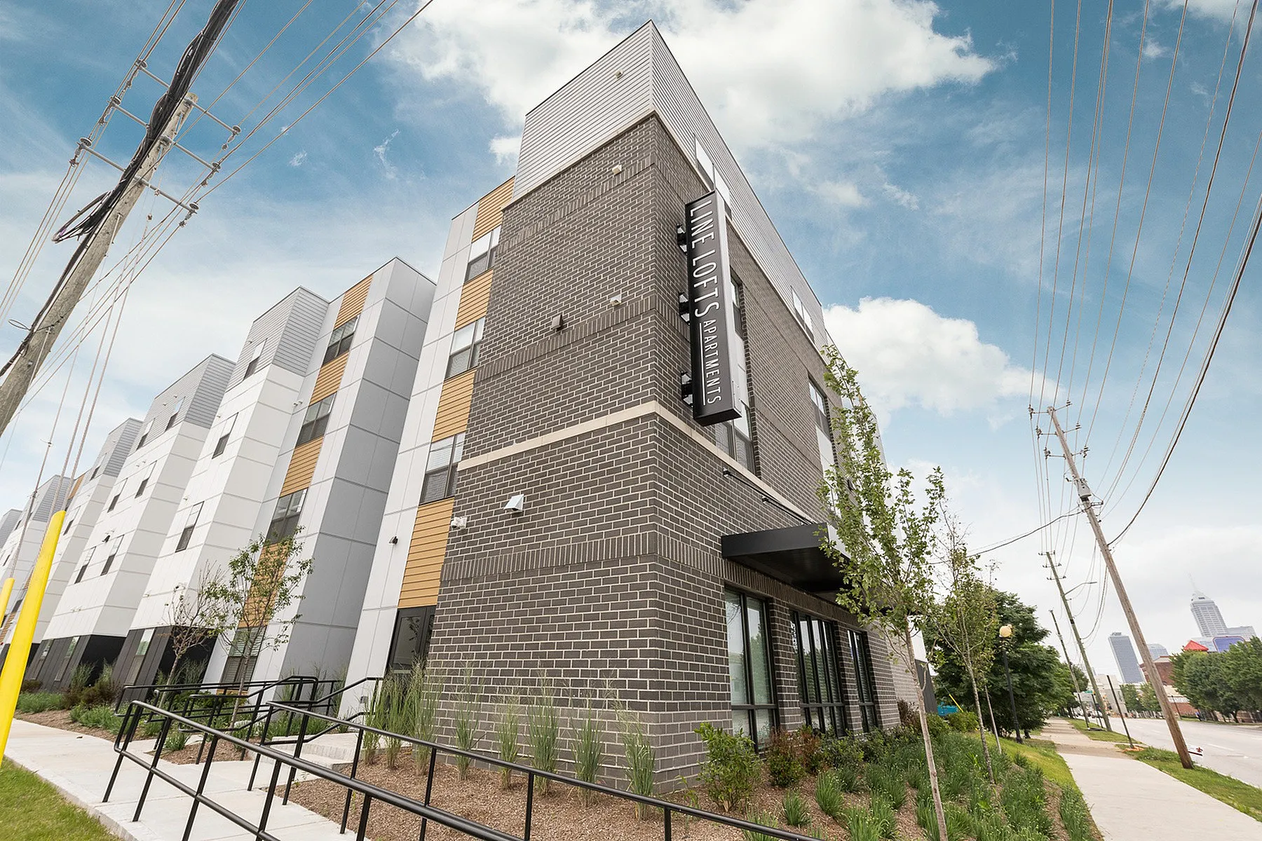 Contemporary apartment building with modern architecture and landscaped entrance, located in a vibrant urban setting.