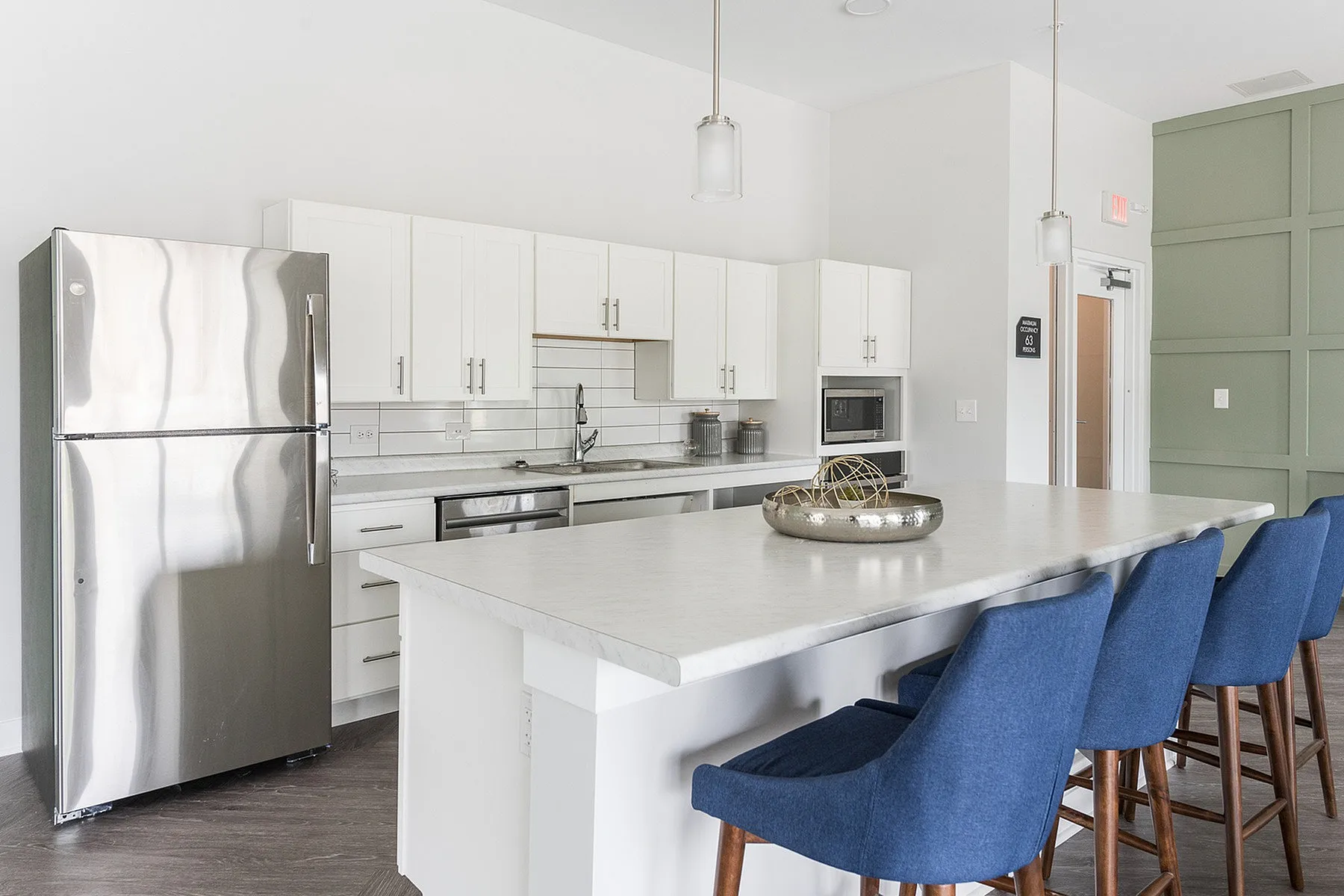 Modern kitchen with sleek white cabinetry, stainless steel appliances, and an inviting island with blue barstools.