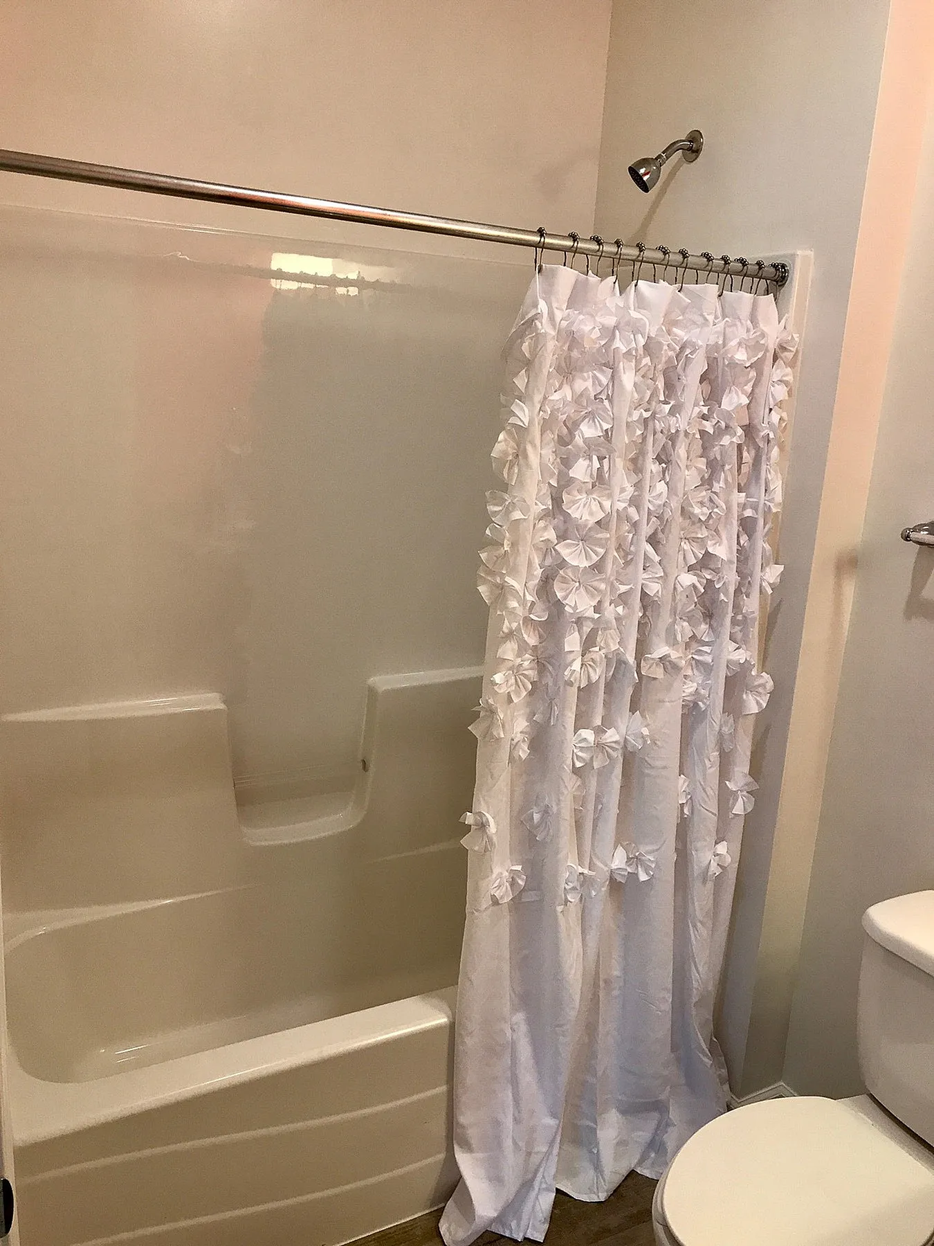 Elegant bathroom with a pristine tub and charming white floral shower curtain, offering a relaxing retreat.