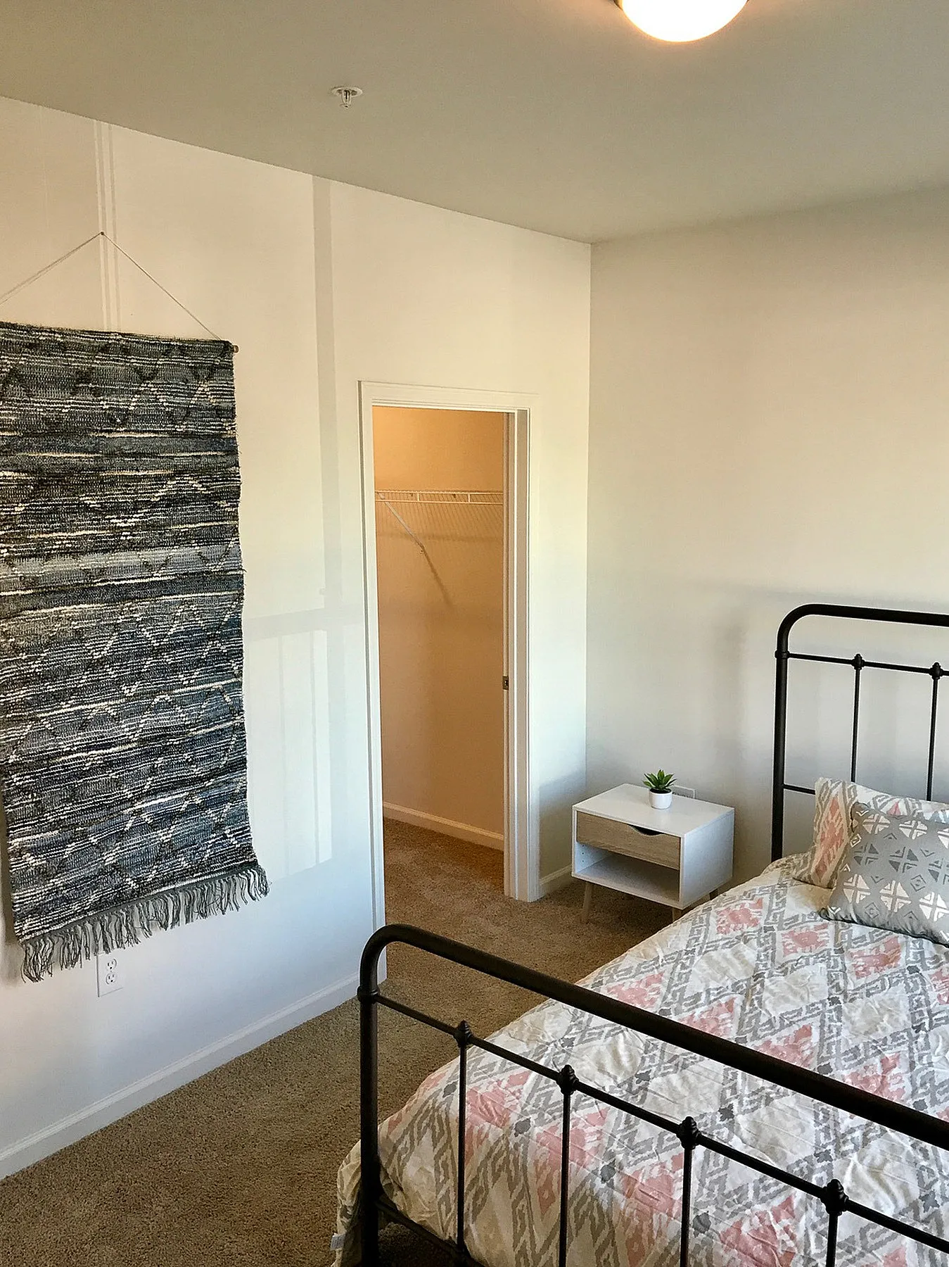 Cozy bedroom featuring a modern metal bed, elegant wall tapestry, and convenient walk-in closet.