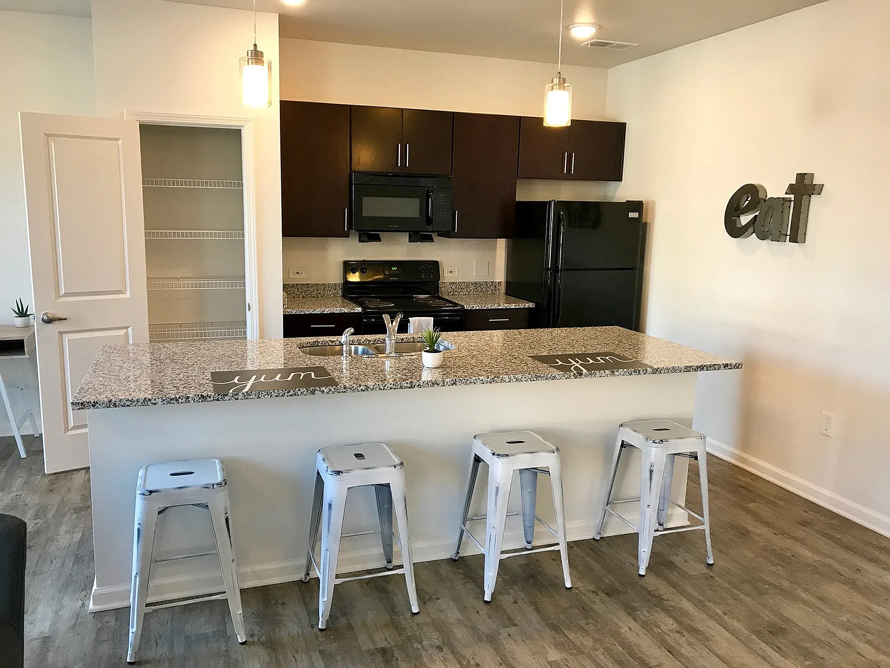 Contemporary kitchen with sleek granite countertops, dark wood cabinets, and chic bar seating; perfect for modern living.