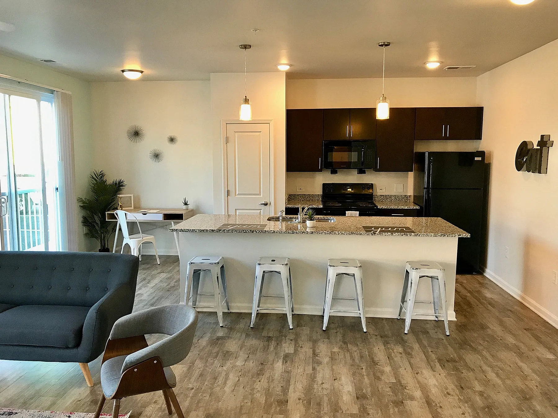 Modern open-concept living area featuring a stylish kitchen with granite countertops, sleek appliances, and inviting bar seating.