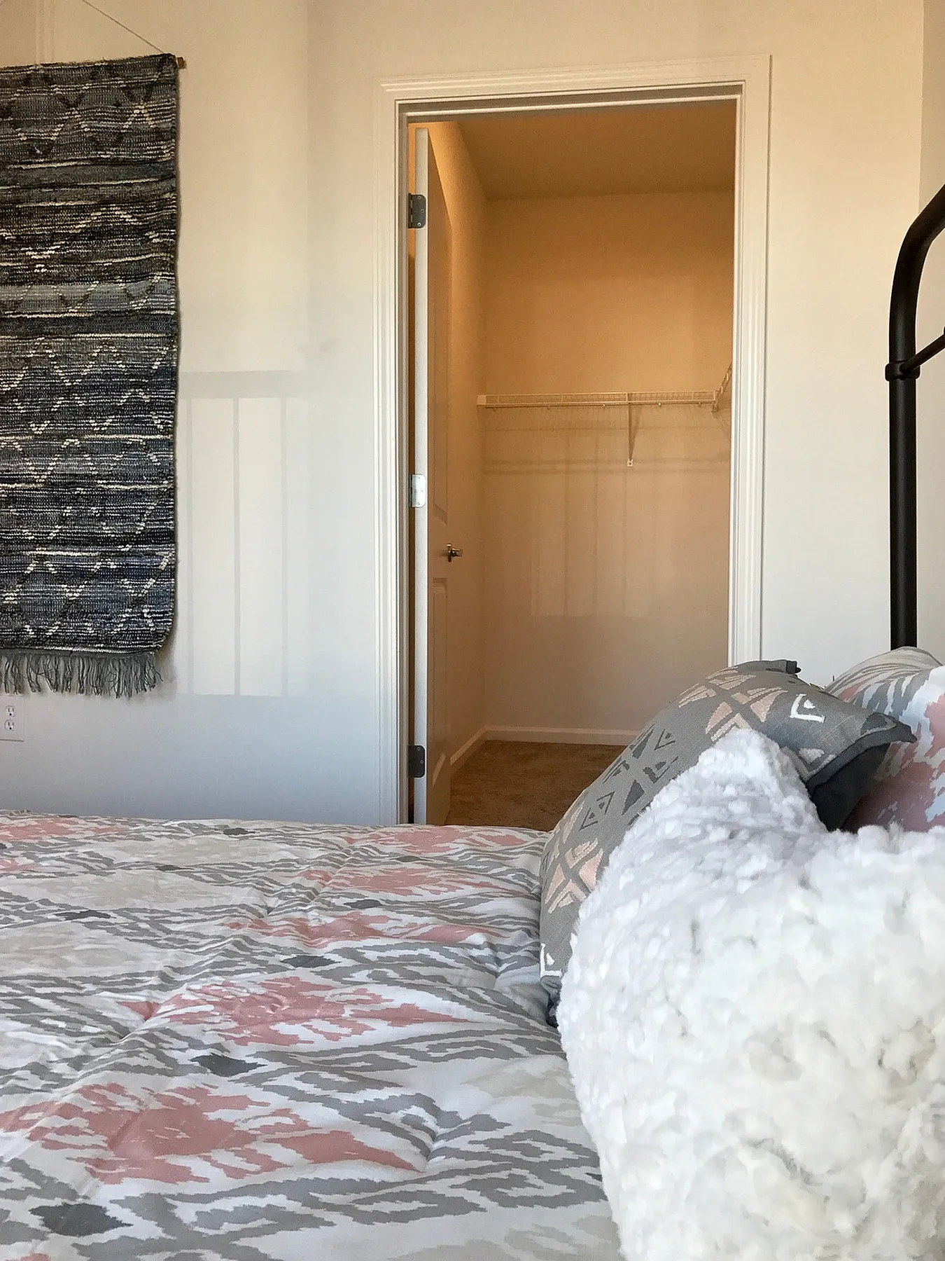 Inviting bedroom with stylish bedding and a walk-in closet, perfect for organized living and comfort.