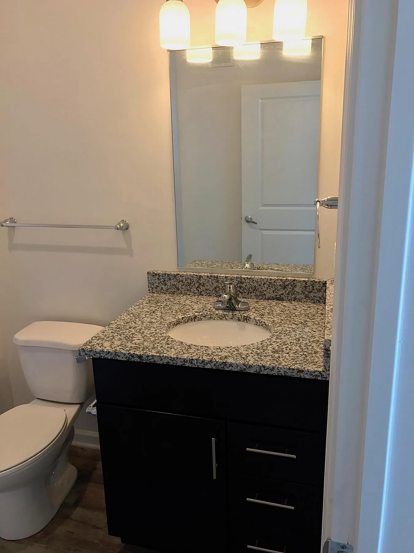 Modern bathroom with elegant granite countertop, stylish vanity, large mirror, and ambient lighting.