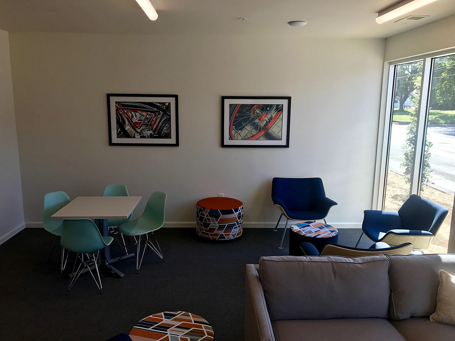 Modern apartment lounge with vibrant seating, abstract wall art, and large windows offering natural light.