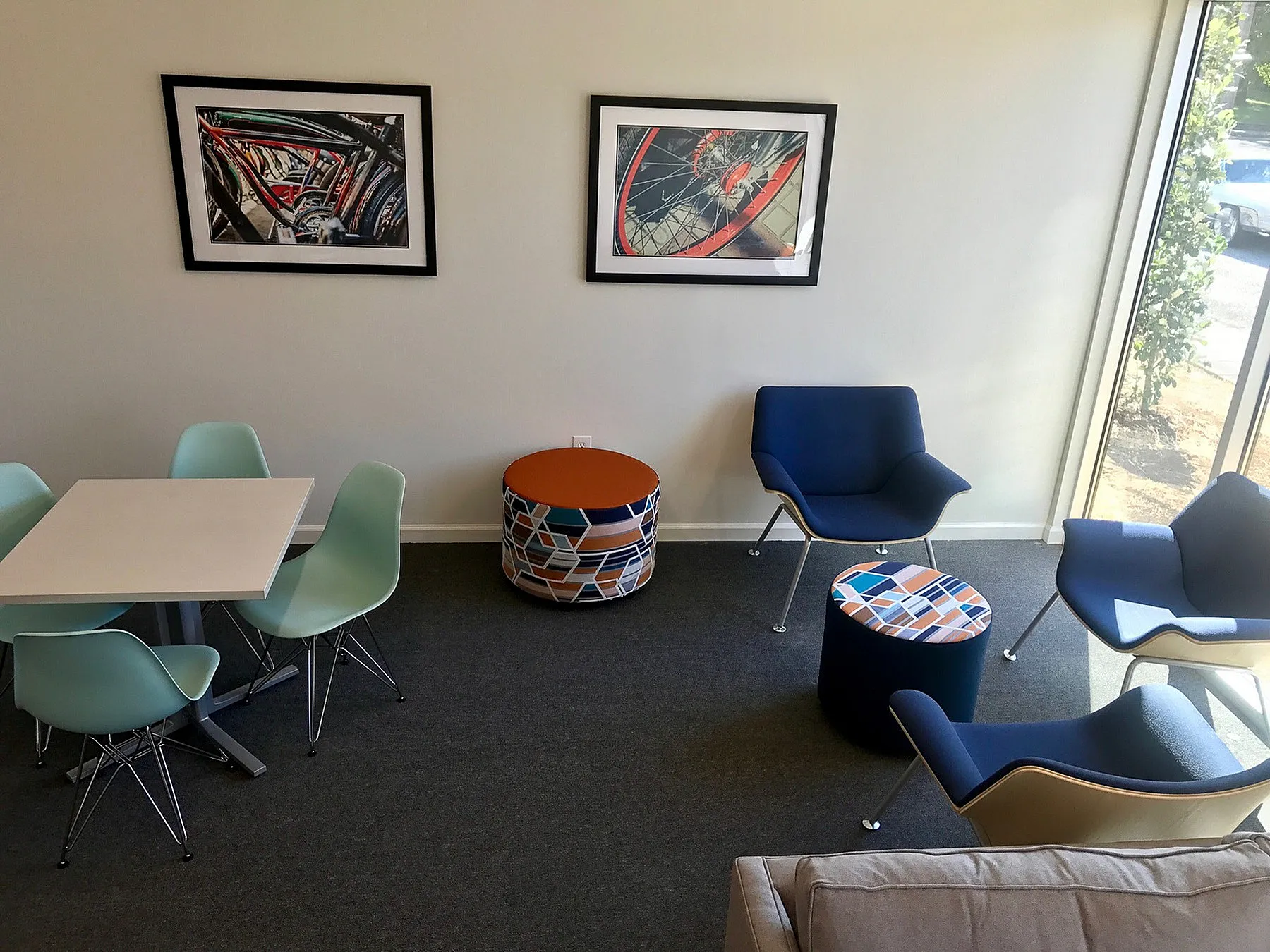 Contemporary living room featuring sleek blue chairs, modern art, and abundant natural light, perfect for relaxation and socializing.