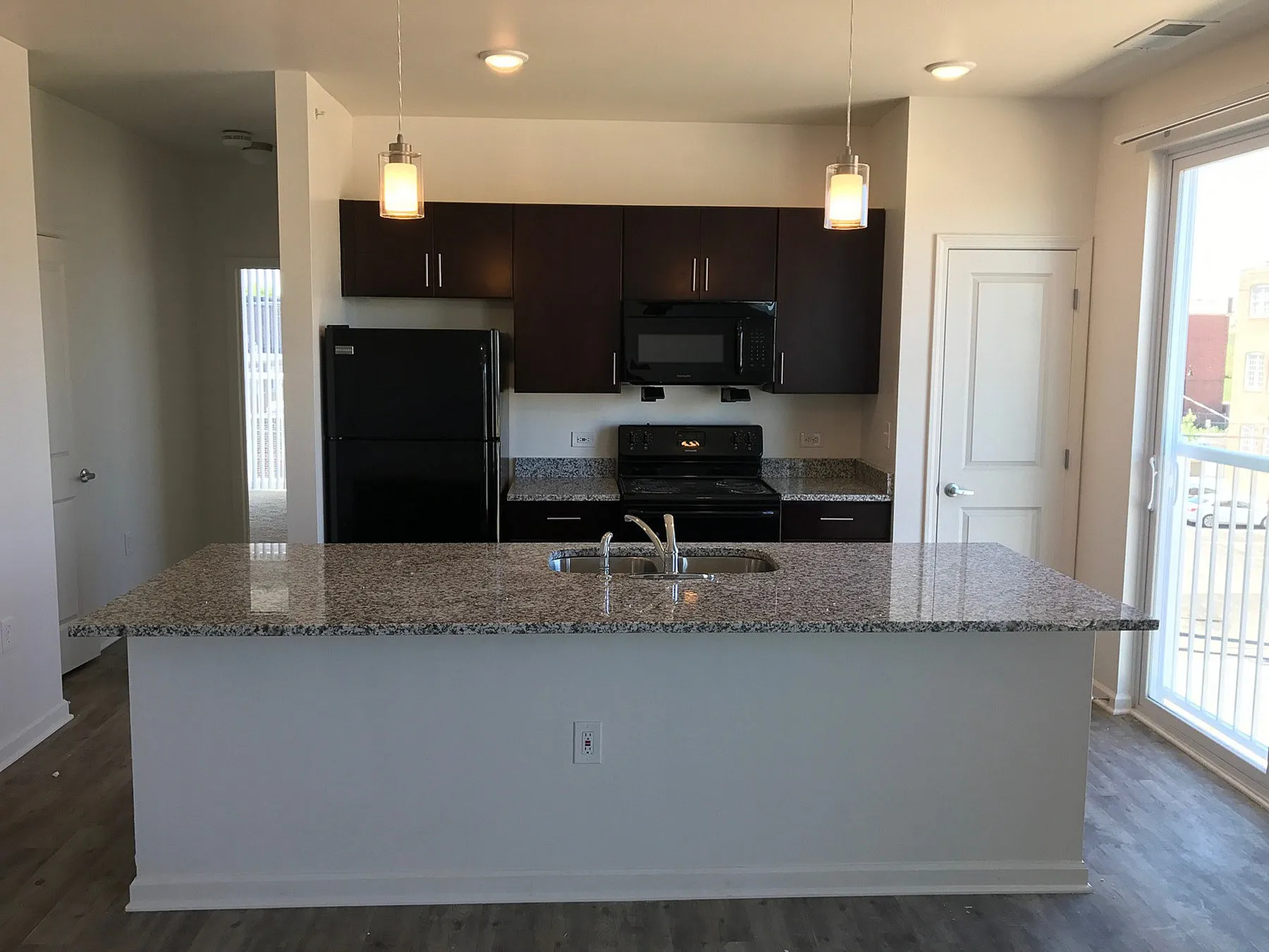 Modern kitchen with sleek granite countertops, elegant pendant lighting, and stainless steel appliances, perfect for culinary enthusiasts.