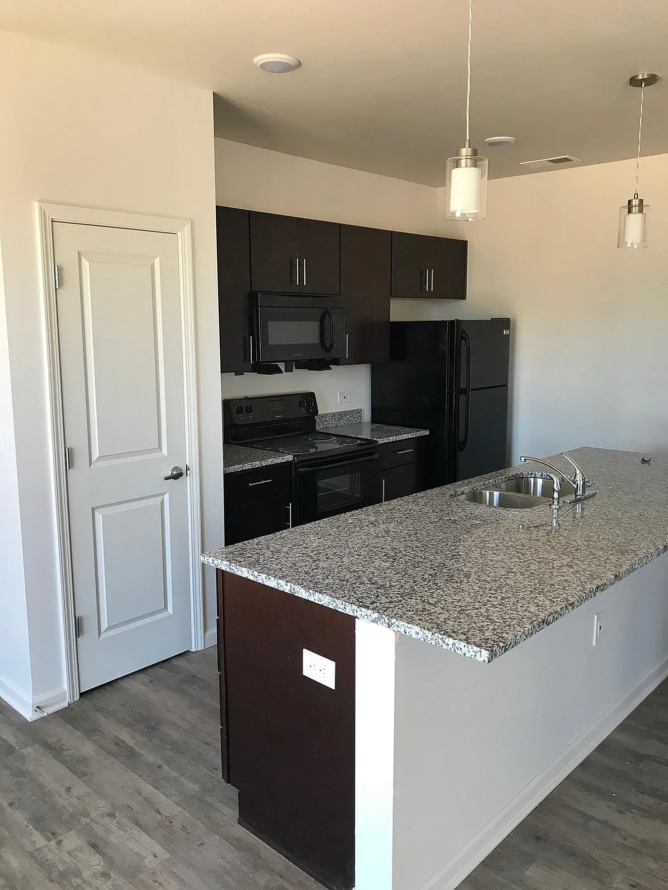 Modern kitchen featuring sleek dark cabinetry, granite countertops, and contemporary lighting.