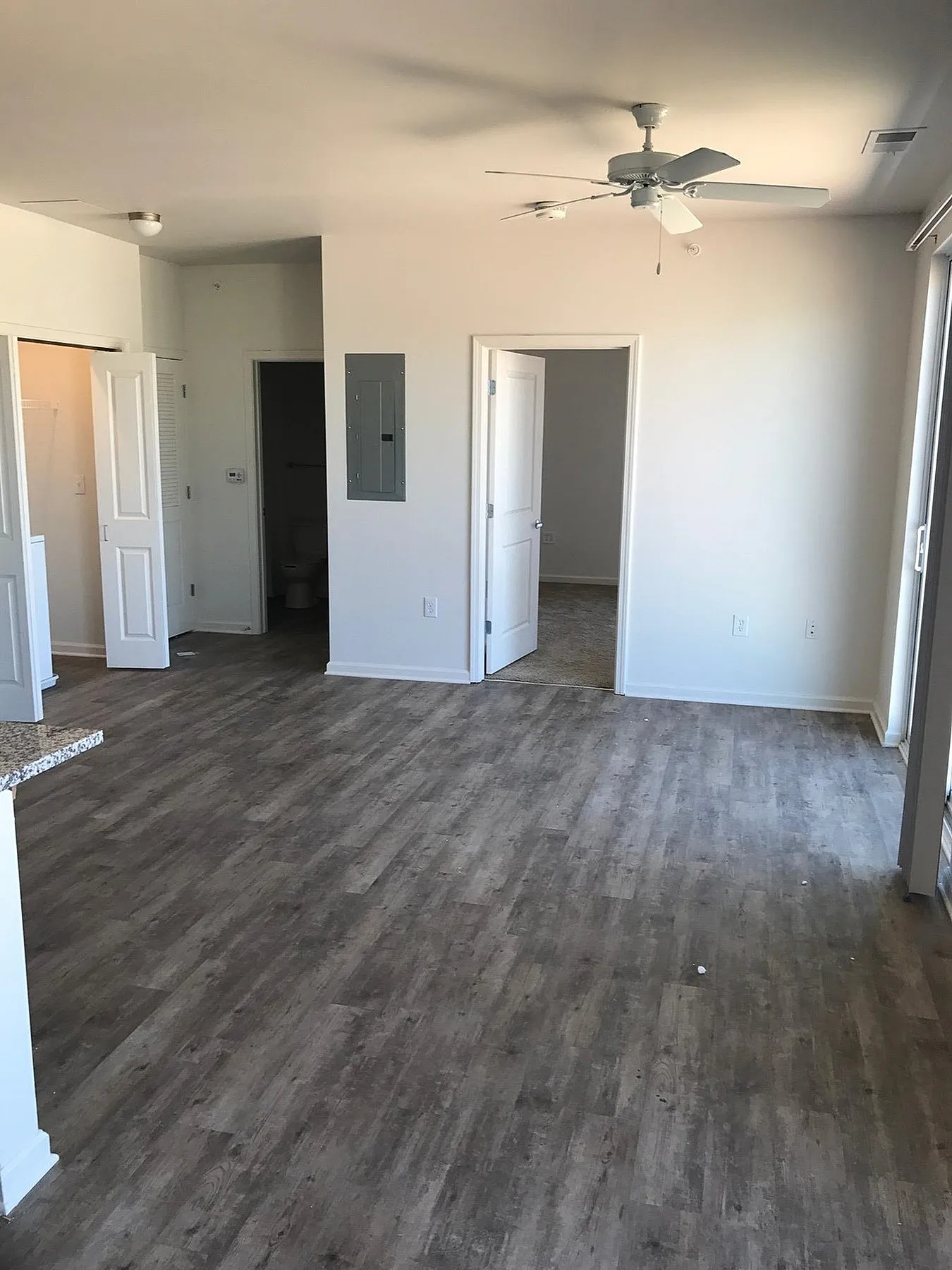 Modern open-plan apartment with elegant wood flooring, bright natural light, and ceiling fan, perfect for comfortable living.