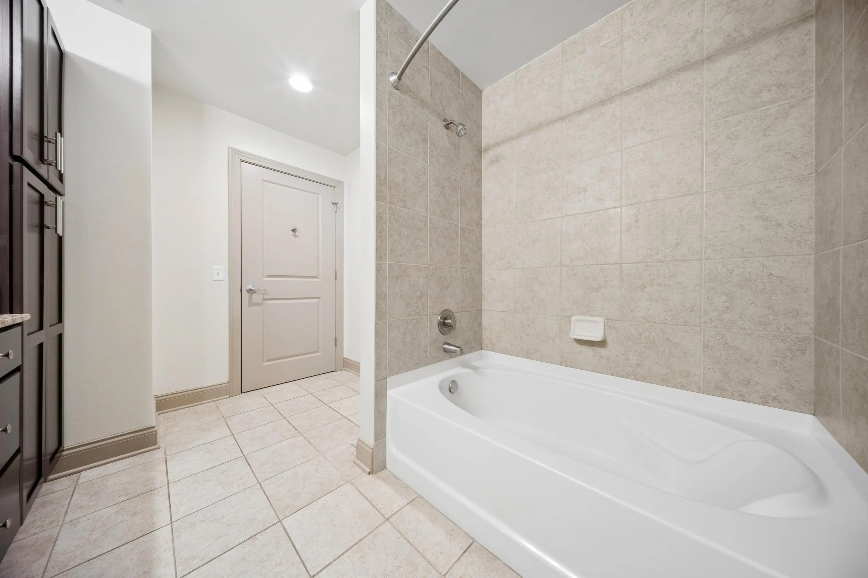 Modern bathroom with elegant tile design, spacious bathtub, and sleek storage cabinets.