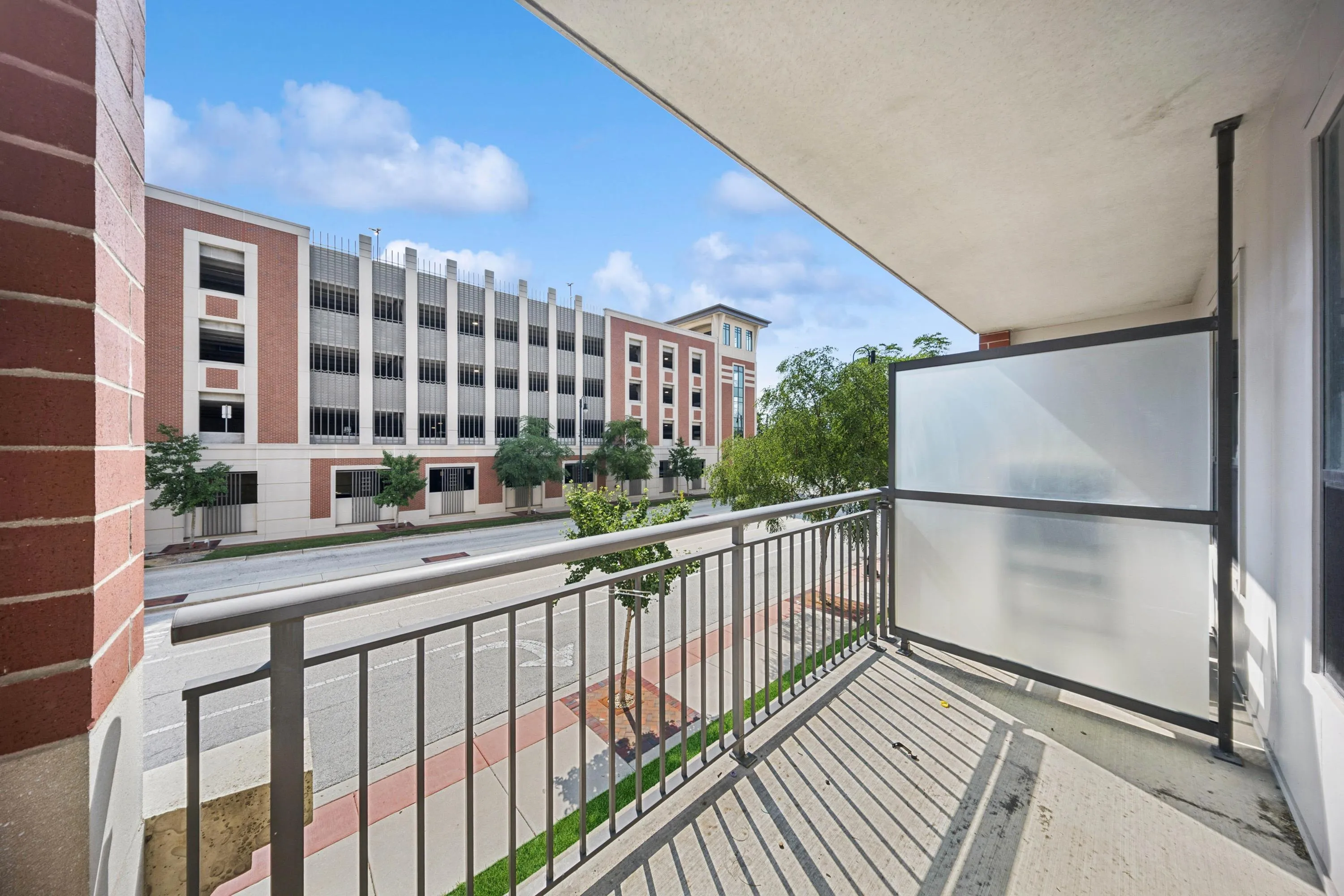 Charming balcony view with modern railing, overlooking a vibrant urban street and stylish architecture.