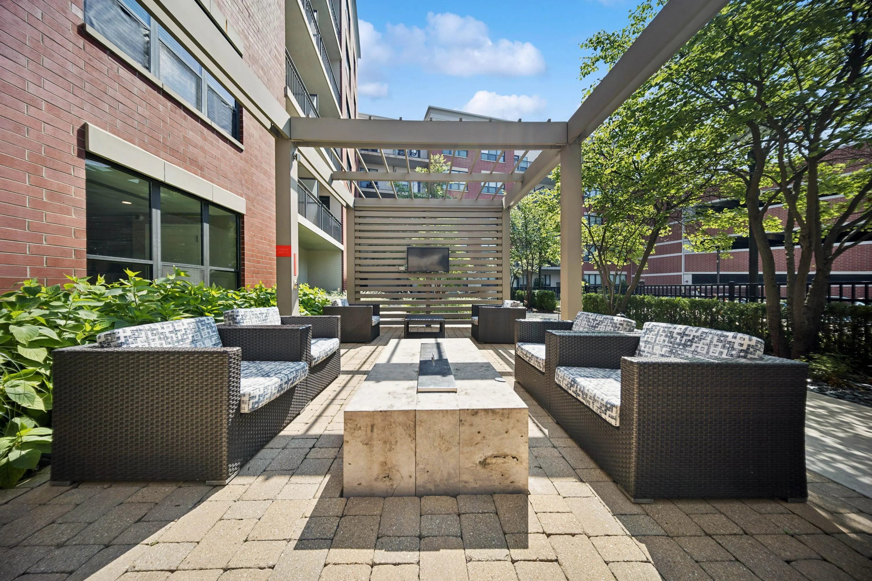 Chic outdoor lounge area with comfortable wicker sofas, elegant pergola, and lush greenery, perfect for relaxation and entertainment.