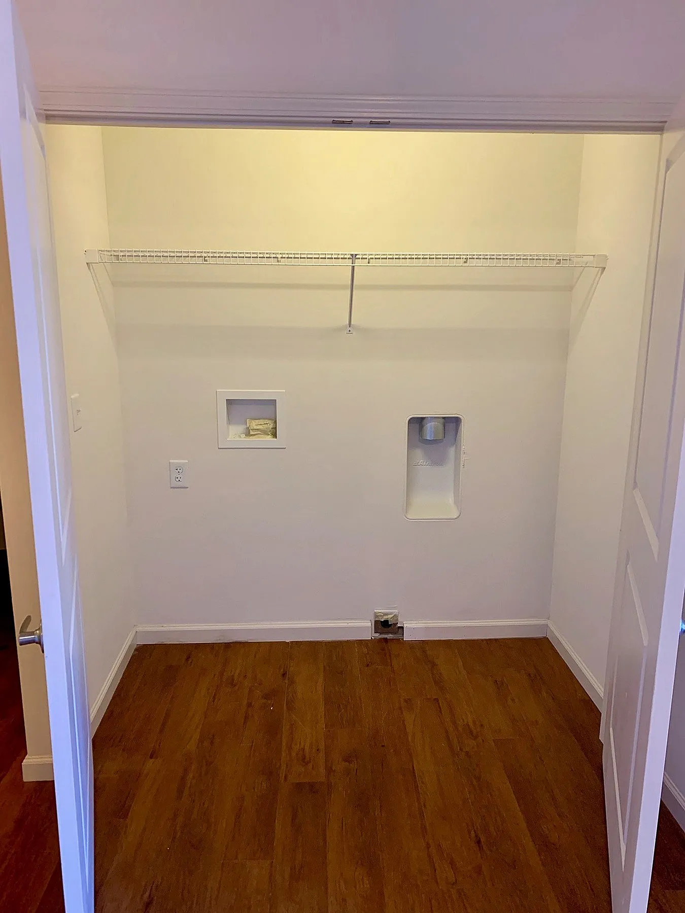 Spacious laundry area with elegant wooden flooring and built-in shelving, perfect for organization.